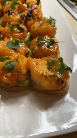 Bang Bang shrimp starters on buttered toasted crostini, avocado lime mousse and microgreens. These will go super fast so make sure you make as many as you can! And make enough because bae is bangin’ 💜 Butterfly the shrimp, de-vein them and batter with salted coconut (shaved) and potato flour (requires egg wash). I seasoned the shrimp also with some salt.  Double fry the shrimp, first flash fry until the batter is hardened, let it rest and flash fry again until crispy.  Bang bang sauce is so easy, Thai red chili sauce, Japanese mayonnaise (kewpie), sriracha sauce, spring onion, garlic powder and slurry together.  Avocado mousse is super blended avocado, half lime and it’s zest, heavy cream and salt, a little olive oil depending on how ripe the avocado is.  As always measure with your heart. 🖤 Piped the creamy dreamy avocado mousse onto the toasted crostini, one lump jumbo shrimp, extra sauce and some beautiful microgreens of your choice.  Crispy, soft, crunchy, tangy and creamy oh man these went super fast and everyone wanted more!  #bangbang #shrimp #avocado #starters #bites #bangin #snacks #viralreel #coconut #lime #avocado #tangy #tiktoksnacks 