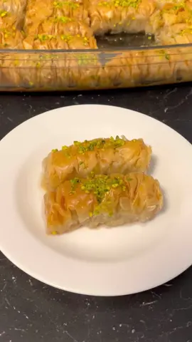 Burma baklava tatlısı tarifi: Malzemeler: 1 Paket baklavalık yufka 200 gr tereyağ Yarım çay bardağı sıvı yağ 1 Kase iri çekilmiş ceviz Şerbet: 3 Su bardağı toz şeker 4 Su bardağı su Çeyrek limon Öncelikle şerbeti hazırlayalım.kıvam alana kadar kaynatıp ocaktan alalım tereyağını eritelim üzerindeki beyaz köpüğü alalım.sıvı yağınıda ekleyip bir kenara alalım.Bir tane yufkamızı alıp üzerini yağlayalım.onun üzerine bir tane daha yufka alıp onuda yağlayalım ve ceviz serpiştirip oklavaya saralım.iki taraftan içeri doğru büzüştürelim ve oklavadan çıkarıp pişireceğimiz tepsiye yerleştirelim.bütün yufkalar bitene kadar aynı işlemi yapalım.kalan yağı üzerlerine sürüp keselim.önceden ısıtılmış 180 derece fırında kızarana kadar pişirelim.tatlı ılık,şerbetin de ilk harlı sıcağı çıkınca tatlıların üzerine dökelim.isteğe bağlı üzerine fıstık serpiştirelim.tatlının üzerini kapatmayalım.çok çıtır ve lezzetli bir tatlı oluyor.Benden söylemesi Not:Yufkaların üzerini nemli bir bezle örtün.yoksa kurur saramassınız. Yapıp deneyecek olanlara afiyet şifa olsun🥰  #baklava #burmatatlisi #baklavatarifi #bayramtatlısı #tatlıtarifi #beautiful #iftaryemeği #lezzetlitarifler #food 