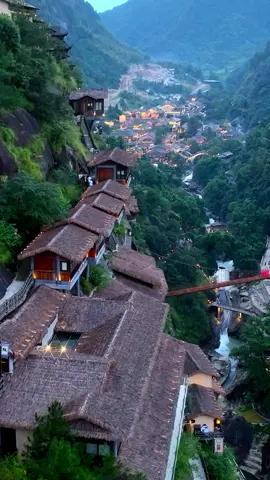 Wangxian Valley is located in Jiangxi, a province in the southeast-central part of China. The scattered wooden houses hang on the cliffs, blending with the mountains in a natural and elegant manner. From a distance, one can see the majestic waterfall and hanging bridges between the mountains, as if entering a world of martial arts, full of fantasy and excitement. #dronevideo #stunning #scenery #mountains  #cliff #houses #fantasy #ChinaNature