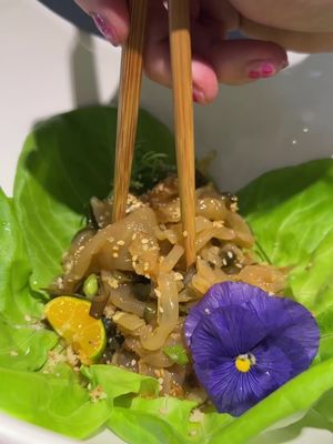 Today I made a jellyfish salad 🪼🪼 When I was in high school I wrote a paper about how I wanted to be a jellyfish because they just float around and don’t have to think about anything 🙈  Jellyfish is a really cool ingredient to use because it has a light salty flavor similar to sea water and a chewy almost crunchy texture- if you’ve ever had agar boba it’s that type of consistency! I like using jellyfish for salads. Today I had some leftover fermented seaweed I added to it. Then I marinated the jellyfish with sesame oil, plum vinegar, yuzu ponzu, and a little bit of chili oil!  My goal was to make the jellyfish look beautiful. So I added butter lettuce to a bowl, then put the marinated jellyfish on top! I garnished with sesame seeds, fried garlic, green onions, Shikuwasa, and a purple pansy! Jellyfish always make me think of sponge bob 😂🙈 #jellyfish #jellyfishsalad #spongebob