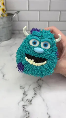SULLEY 🩵💜 Turning a cupcake into Sulley 🩵💜 #monstersinc  I used buttercream to attach Oreo halves to the bottom of the cupcake. I used piping tip 233 to pipe his fur in purple and turquoise. I added his teeth using a small round piping tip and white buttercream. The eyes, nose and horns are made from fondant.  I love him 🩵💜 can you guess who’s coming next? 🤔👀💚 #cupcake #cakedecorating #sulley #monstersinc #cakedbyrach #cakeartist #pixar #caketok 