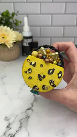 Handbag cupcakes 🐆🖤💛👜 Use black chocolate drip to add dots onto parchment paper. Let them set. Pipe caramel coloured buttercream onto your cupcakes.  Press them onto the dotted parchment paper. Freeze them for 15 minutes. Remove them from the paper and chop a piece of buttercream from the top of the cupcake. Add some sprinkles and gold leaf. Then attach a little fondant handle. #cupcake #cakedecorating #colourmill #cakedbyrach #handbag #leopardprint #cutefood #cakedesign 