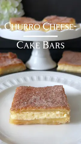 Churro Cheesecake Bars Recipe 🤍 This recipe for Churro Cheesecake Bars combines the delicious, crispy texture of churros with a creamy cheesecake filling.🥰 📝 Ingredients:   For the Cheesecake Layer: - 450 g cream cheese, unsalted - 150 g sugar - 1 tbsp cornstarch - 2 eggs (medium) - 2 tsp vanilla extract   For the Churro Layer: - 2 rolls of puff pastry (from the refrigerated section) - 50 g sugar - 1 tsp ground cinnamon 🤍  Instructions: 1. Preheat the oven to 180°C (350°F). Grease a rectangular baking pan (27 x 17 cm). 2. In a large bowl, beat the cream cheese, sugar, and cornstarch until smooth. Add the eggs and vanilla extract, and mix well. 3. Roll out one sheet of puff pastry and place it in the prepared baking pan. Trim any excess edges. 4. Spread the cheesecake mixture evenly over the bottom puff pastry layer. Roll out the second sheet of puff pastry and place it on top of the cheesecake mixture. Trim the edges as needed. 5. In a small bowl, mix together the sugar and cinnamon. Sprinkle this mixture evenly over the top puff pastry layer. 6. Bake the bars in the preheated oven for about 30 minutes, until the top layer is golden brown and the puff pastry is puffed up. 7. Let the bars cool completely in the baking pan before cutting them into squares. Enjoy these delicious Churro Cheesecake Bars 🤍