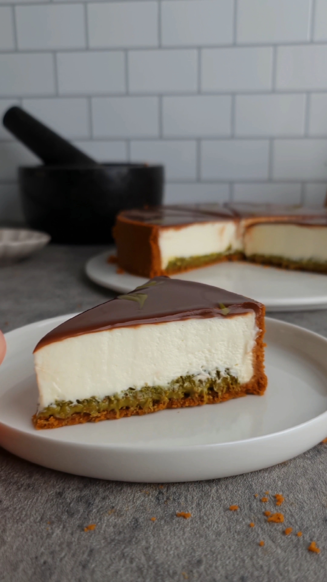 Cheesecake pistache sans cuisson  la base :  200g de biscuits  90g de beurre  Mixer les biscuits, ajouter le beurre fondu, verser dans votre moule, étaler puis réserver au frais le temps de préparer la garniture. l'insert pistache  une poignée de cheveux d’ange  2càs de pâte de pistache  1càs de pâte de sésame(tahini) Faire dorer les cheveux d’ange quelques minutes dans une poêle avec une noisette de beurre. Ajouter la pâte de pistaches et la pâte de sésame, mélanger puis étaler le tout sur la base du cheesecake. la crème : 300g de crème au fromage à température ambiante  25g de sucre  150g de crème montée froide  la ganache :  100g de chocolat  100g de crème  Mélanger le fromage avec le sucre, ajouter la crème montée froide puis étaler le tout sur la couche pistache. Réserver au frais minimum 4hr avant de démouler. Faire bouillir la crème et verser sur le chocolat, Verser la ganache sur le cheesecake. 🇺🇸 No-bake pistachio cheesecake  the base : 200g biscuits 90g butter Mix the biscuits, add the melted butter, pour into your mold, spread then refrigerate while you prepare the filling. the pistachio insert a handful of angel hair 2 tbsp pistachio paste 1 tbsp sesame paste (tahini) Brown the angel hair for a few minutes in a pan with a knob of butter. Add the pistachio paste and sesame paste, mix then spread everything over the cheesecake base. cream : 300g cheese cream at room temperature 25g of sugar 150g cold whipped cream the ganache: 100g of chocolate 100g of cream Mix the cheese with the sugar, add the cold whipped cream then spread everything over the pistachio layer. Refrigerate for at least 4 hours before unmolding. Boil the cream and pour over the chocolate. Pour the ganache over the cheesecake.