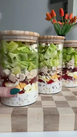 Cobb salad jars are my new obsession. This recipe makes 3-4 jars! Ingredients 1 rotisserie chicken 8 oz turkey bacon  4 hard boiled eggs 1 can corn 1/2 a red onion, diced 1 pint cherry tomatoes, quartered  Romaine lettuce, chopped Reduced fat feta cheese Dressing 1/2 cup nonfat plain Greek yogurt 1-2 tbsp ranch seasoning (adjust according to taste preference) Unsweetened almond milk to thin Instructions 1. Make your hard boiled eggs then set aside to cook before peeling. While eggs boil, preheat oven to 350 F and add turkey baking to a large baking sheet, bake for around 15-20 min or until crispy. 2. While turkey bacon cooks diced rotisserie chicken into bite sized pieces and chop your veggies.  3. Whisk together dressing ingredients slowing adding almond milk until you reach your desired consistency. Add more ranch seasoning as needed. 4. Once turkey bacon and eggs are cooled, chop into small pieces. 5. Layer ingredients in glass jars starting with dressing then add corn, onion, tomatoes, egg, bacon, chicken, romaine, and feta. Serve with avocado if desired. 6. Store in fridge for up to 4 days. #saladrecipe #saladsoftiktok #mealprep #highproteinmeals 