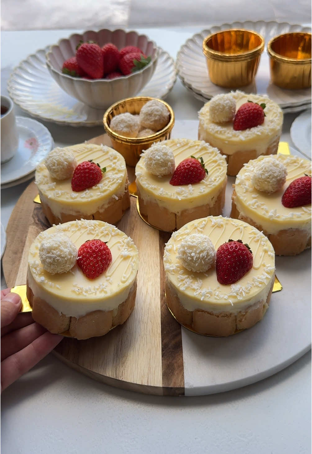 Todays Kitchen: COCONUT DESSERTS (NO BAKE) #food #Recipe #dessert #coconut #tasty #nobake #fy #fyp #foryoupage CREAM LAYER ▫️200 gr cream cheese ▫️8 gr vanilla sugar (1 tbsp) ▫️50 gr powdered sugar ▫️16 gr whipped cream stabilizer (2 tbsp, klopfix) ▫️300 ml heavy cream ▫️40 gr grated coconut CHOCOLATE GANACHE ▫️100 ml heavy cream  ▫️200 gr white chocolate OUTER LAYER ▫️ladyfingers (milk variety) FILLING ▫️coconut cookies GARNISH ▫️strawberries ▫️grated coconut Place the cream cheese, vanilla sugar, powdered sugar, and whipping cream stabilizer in a deep bowl. Mix for 1 minute on low speed. Gradually add the heavy cream, mixing until the cream becomes firm. Next, add the grated coconut and mix briefly until well combined. Heat the heavy cream for the ganache until almost boiling. Add the white chocolate, let it sit for 1 minute, and then stir until smooth. Fill separate piping bags with the cream and the white chocolate ganache. If you don't have piping bags, sandwich bags can be used as a substitute. Cut the ladyfingers into thirds. Take one piece and divide it again into three smaller pieces for the dessert’s base layer. Repeat this process until you have enough pieces. Line the bottom of a cake ring (8 cm) with plastic wrap and place it on a plate or coaster. Arrange the ladyfingers along the edges of the cake ring and cover the base with the smaller pieces. Layer the dessert inside the ring: first, pipe a layer of cream onto the base, followed by a layer of white chocolate ganache and a piece of coconut cake. Then, add another layer of cream. Ensure you leave enough space for the final ganache layer on top. Smooth the surface and pipe a thin layer of ganache over the dessert. Let the dessert set in the fridge for at least 4-5 hours, but preferably overnight, to allow the cookies to soften. Before serving, garnish with chocolate drizzle, halved strawberries, and grated coconut.