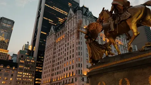 The sun was setting, casting long shadows across the busy streets of midtown Manhattan. People hurried along the sidewalks, their heads down, focused on their destinations. The air was thick with the sounds of traffic, honking cars, and the chatter of pedestrians. The towering skyscrapers loomed overhead, their windows reflecting the fading light. A few street vendors hawked their wares, their voices barely audible over the din. In the distance, the iconic Plaza Hotel stood majestically, its golden façade gleaming in the last rays of sunlight. #nyc #newyork #nyclife #eveningwalk #midtown #fyp 