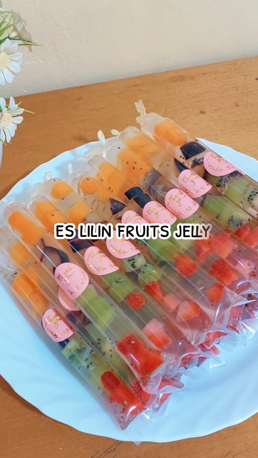 resep es lilin fruits jelly 🥭🍇🥝🍓 Bahan :  • Buah Strawberry • Buah Kiwi • Buah Anggur • Buah Mangga • nutrijell leci / nutrijel plain • 200 gr gula pasir • 700ml air • Chia seed / selasih  Cara: Potong kecil buah-buahan. Masukkan buah dalam plastik es lilin. Masak nutrijell sesuai petunjuk. Tambahkan chia seed ke dalam jelly. Tuang jelly lalu Ikat. Tunggu set, dinginkan!!  happy recook moms🥰 #reseptiktok #resepsimple #resepeslilin #eslilin #eslilinmakassar #pabalueslilin #eslilinbuah #eslilinjelly #eslilinkekinian #eslilinjadul #eslilinpopice #esmambo #esmamboviral 