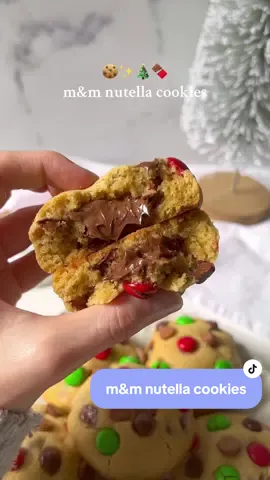 M&M Nutella cookies 🍪 the yummiest way to get into the holiday spirit ✨ Ingredients: -120g salted butter (softened) -100g light brown sugar -80g caster sugar  -2 tsp vanilla extract -1x egg (room temperature) -300g plain flour -1 tsp baking powder -1/2 tsp baking soda  -Nutella (approx 14 tsp) -Chocolate chips and m&ms (measure with ❤️) Method: -Scoop approximately 1 heaped tsp of Nutella and place on a lined tray/plate. Repeat this until you have 14 ‘blobs’. Place in the freezer to harden. -Whisk butter, light brown sugar and caster sugar until combined. -Whisk in egg and vanilla extract. -Fold in flour, baking powder and baking soda. -Fold in chocolate chips. -Take approximately 60g of cookie dough and press it out in your hand. Place the frozen Nutella in the centre and wrap the cookie dough around the Nutella. Roll into a ball. Add m&ms and choc chips on top of the cookie dough ball. -Chill the cookie dough balls for 1-2 hours. -Preheat oven to 180C (356F). -Bake at 180C for 15-20 minutes or until the edges are golden brown. Happy Baking! #cookies #nutellacookies #cookierecipe #baking 