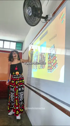 Trabalhamos alguns povos e tecidos africanos, como o Samakaka do povo Mumuíla, e eles amaram ver ao vivo! A aula sempre fica mais legal assim, né? Já viu esse tecido por aí? Descrição: Sou uma mulher negra de pele clara, com cabelos cacheados na altura dos ombros. Estou usando óculos grandes de armação preta e brincos compridos. Visto uma regata preta e uma saia estampada com padrões coloridos geométricos em tons de vermelho, amarelo, preto e branco. #Educacao #SalaDeAula #EducacaoPublica #Escola #EscolaPublica #Professores #Alunos