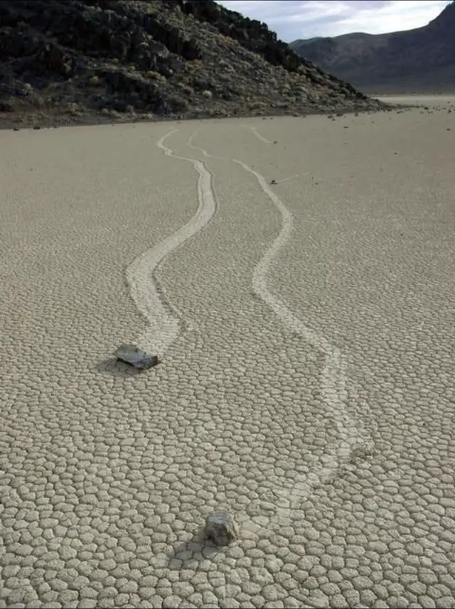 Sailing Stones of Death Valley in California. These stones mysteriously move across the desert floor, leaving long trails behind them. Photographs and time-lapse evidence show that thin layers of ice form during rare rain events. When the ice melts and the wind blows, it creates just enough force to push the stones across the muddy surface, carving those trails. This combination of environmental factors is rare, making the movement of these stones a fascinating natural puzzle that has now been solved and photographed. #fyp #deathvalley #phenomenon #facts #nature 