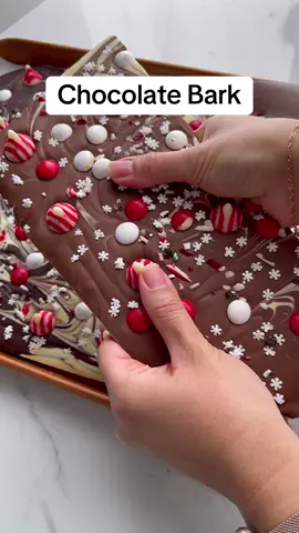 Easy Chocolate Bark! Preheat oven to 170°F Placed dark, milk and white chocolate on a parchment lined baking sheet, bake for 10 minutes. The chocolate will be perfectly melted to create those beautiful swirls using a wooden skewer.  While the chocolate was still wet, I added toppings.  I used candy cane chocolate kisses, peppermint M&m’s, crushed candy cane and snowflake sprinkles.  Place tray in the freezer for 20-30 minutes then break into pieces.  #xmasrecipes #chocolatebark #chocolate #easydessert #fyp #fypp 
