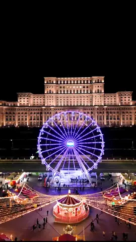 What does Christmas magic mean to you? In Bucharest, it unfolds spectacularly in front of the grandiose Palace of the Parliament. A towering Christmas tree, resplendent with shimmering lights, stands as the centerpiece. Nearby, a Ferris wheel spins lazily, its spokes adorned with luminescent strands that glint against the winter night. All of this under the gilded glow of one of the world’s largest and most opulent administrative buildings—a modern colossus wrapped in festive cheer. This is no ordinary market; it is a gathering steeped in both nostalgia and modernity. The Palace of the Parliament, a structure of staggering proportions and history, commands the skyline. With over 3,000 rooms and 330,000 square meters of space, it’s one of the heaviest buildings in the world—an architectural testament to ambition. But tonight, it serves as a luminous backdrop to a sea of twinkling fairy lights, artisanal stalls, and families wrapped in scarves, sipping hot mulled wine. Could there be a more fitting place for a Ferris wheel to rise beside such grandeur? The tree’s twinkling branches evoke the whisper of ancient forest lore, while the bustling market echoes with the laughter of countless visitors. Is this where your next Christmas story begins? Video by @drone.patrol  [Christmas Market, Bucharest, Palace of the Parliament, Romanian Winter, Festive Atmosphere, Christmas Lights, Giant Tree, Winter Ferris Wheel, Holiday Magic, Seasonal Traditions, Romanian Culture, Urban Festivities, Mulled Wine, Artisan Crafts, Snowy Market, Historic Landmarks, Night Photography, Architectural Marvel, European Christmas, Traditional Foods, Winter Wonderland] #romania #bucuresti #travel #christmasmarket #holidayseason #romaniatravel #festivevibes #europeanadventure #lights