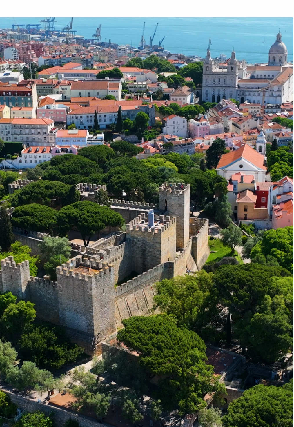 The Castle of São Jorge is a key historic site in Lisbon, sitting on a hill in the Alfama district. It dates back to the 11th century when it was built by the Moors as a military stronghold. After the Reconquista in 1147, it was taken by King Afonso Henriques and became a royal residence. The castle remained an important defensive structure until the 16th century when it began to lose its military significance. The castle complex includes 11 towers, with the Tower of Ulysses housing a Camera Obscura that provides a unique 360° view of Lisbon. The Archaeological Site showcases remnants from various periods, including Iron Age, Roman, Visigoth, and Moorish settlements, highlighting the area’s continuous human habitation for centuries. Excavations have uncovered Roman mosaics, medieval cisterns, and Moorish foundations. The site also features a small museum displaying items like pottery, tools, and coins discovered on-site. The castle was heavily restored in the 20th century, especially under dictator António Salazar, to preserve its historical importance. The walls and battlements offer some of the best views of Lisbon, overlooking the Tagus River, the 25 de Abril Bridge, and the Christ the King statue. The castle also has a garden with native plants and peacocks roaming freely, adding to its appeal as a visitor attraction.  #Lisbon #Portugal  #TagusRiver #PombalineArchitecture #HistoricLisbon #VisitPortugal #LisboaVibes #TravelEurope #PortugueseHistory #DroneViews #DronePortugal #CitySquares #ArchitectureLovers  #DiscoverPortugal #EuropeanCapitals #LisbonPhotography #CulturalHeritage #TravelLisbon #HistoricLandmarks #LisbonSights #ExploreLisbon #WorldHeritageSites #LisbonTourism #TravelGoals #lisboaportugal #portugal🇵🇹 #LisbonCastle #CastleofSãoJorge #SãoJorgeCastle #LisbonViews #HistoricalLandmarks #PortugalTravel #MedievalHistory #VisitLisbon  #TravelEurope #CastlesOfEurope #PortugueseHistory #ArchaeologicalSite #TagusRiverViews #HistoryLovers #CulturalHeritage #LisbonTourism #TopLisbonAttractions #TravelTikTok #BucketListDestinations