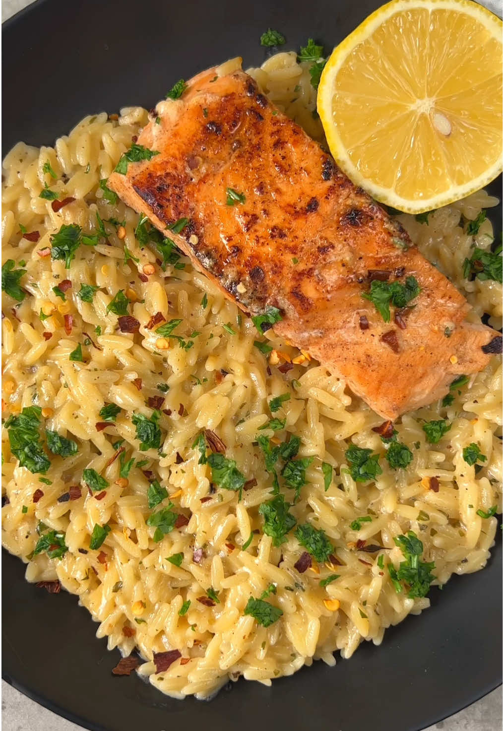 الذ سالمون بالكريمة والليمون🍣 Garlic and lemon Salmon with risotto  @passion.kitchen1 المقادير والطريقة: شرايح سالمون  لتتبيلة السالمون: ١ م ك زيت زيتون ١ م ك خردل ١/٢ عصير ليمون  ١ فص ثوم مهروس (بابريكا - بودرة ثوم - ملح - فلفل اسود- ملح ) للريزيتو: ٢ م ك زيت زيتون ٧ فصوص ثوم مهروس ١ م ص اوريقانو او اكليل الجبل او اي بهارات ايطالية ١ مكعب مرق دجاج او ١ كوب مرق دجاج ٤٥٠ جرام ريزيتو  ٢ و١/٢ ك ماء ١/٢ كوب كريمة طبخ ١/٢ كوب بارميزان ٢ م ك بقدونس مفروم  عصير ليمونة فلفل احمر مجروش - ملح - فلفل اسود  . يتبل السالمون ويترك جانباً ١٥ دقيقه حتى يتنكه  في تاوه يسخن زيت الزيتون ثم يشوى السالمون تقريبا على كل جهه دقيقتين ثم يرفع ( نتجنب الطبخ الزائد لانه سيعاد طبخه مع الريزيتو ) في نفس التاوه يسخن زيت الزيتون والثوم المهروس ثم الاوريقانو ومرق الدجاج ثم الريزيتو ثم الماء ثم يغطى ويترك على نار هادئه ٨ دقايق  تضاف كريمة الطبخ والجبن والبقدونس والبهارات ثم يضاف السالمون ثم عصير الليمون ويغطى ويترك دقيقتين حتى تتسبك ثم ترفع وتقدم وبالعافية .. #الشعب_الصيني_ماله_حل😂😂 #غداء #عشا #سالمون #سلمون #اكل_صحي #salmon 