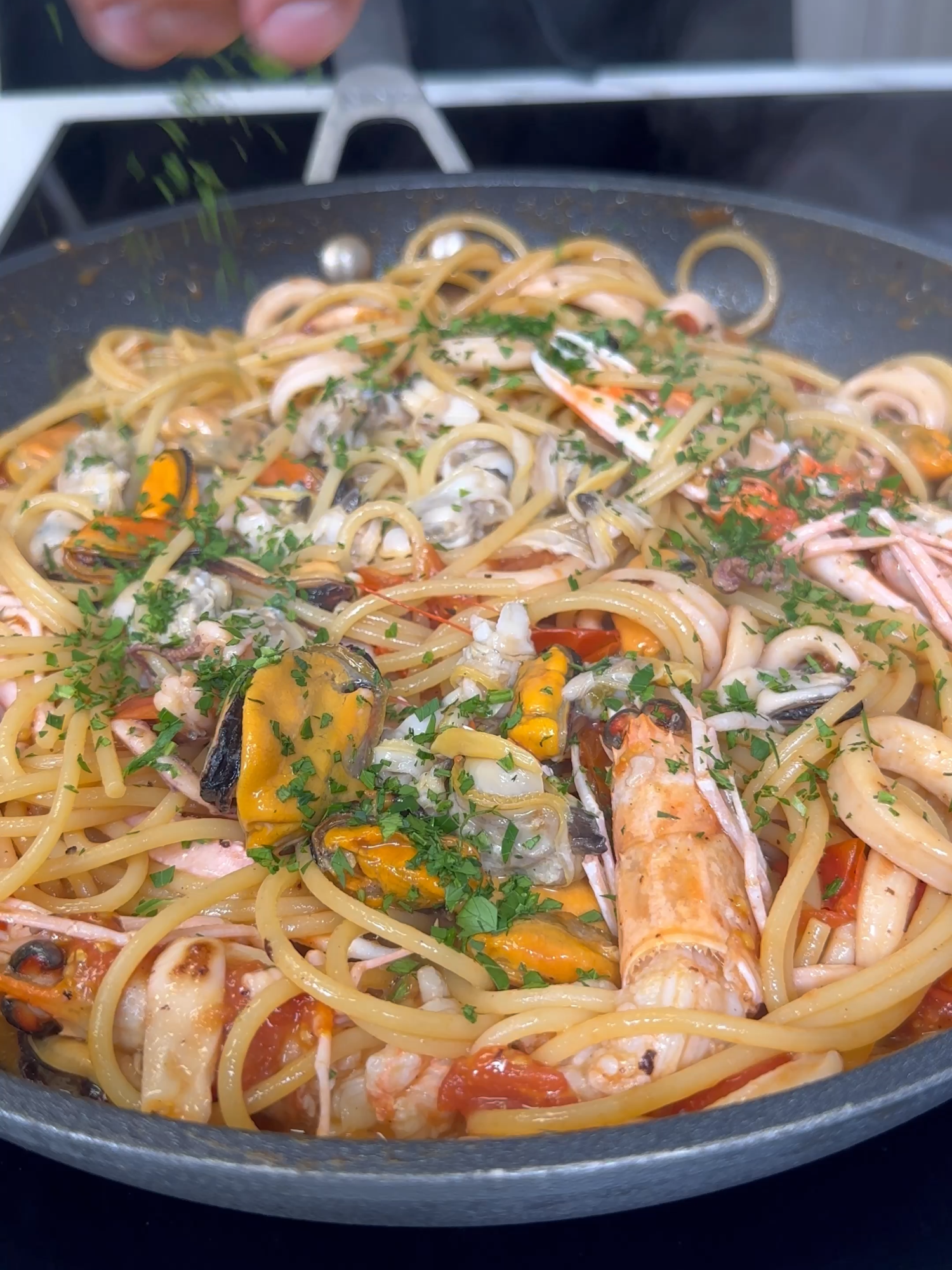 The perfect dish to prepare during holidays? Spaghetti allo Scoglio! 🌊🍝  @sebastian_fitarau Fresh mussels, clams, squid, and langoustines come together in this Italian classic. 💫✨ Spaghetti: 1 ½ cups (320 g) Mussels: 2 ¼ lbs (1 kg) Clams: 2 ¼ lbs (1 kg) Squid: 10 ½ oz (300 g) Langoustines: 8 Cherry tomatoes: 2 cups (300 g) Extra-virgin olive oil: 4 tbsp Garlic: 1 clove Parsley: 1 small bunch White wine: 2 ¾ tbsp (40 g) Fine salt: to taste Black pepper: to taste Instructions: Prepare the Mussels and Clams: Rinse clams under running water several times, then soak in cold water. Scrape mussels clean, removing the beard. Use a steel wool pad to clean their shells. Before cooking, tap each clam on a cutting board or sink with the shell's edge facing down. Discard any that do not close. Heat oil in a large pan. Once hot, add clams and mussels. Cover with a lid and cook for 3–4 minutes until shells open. Remove the lid and set the seafood aside. Shell most mussels and clams, reserving some with shells for garnish. Clean the squid and langoustines. Wash cherry tomatoes and cut them into wedges. Bring water to a boil, salt it, and cook spaghetti. Reserve 5 minutes of cooking time to finish in the sauce. In the pan, sauté garlic in oil until golden. Add squid and a pinch of salt. Cook for 5 minutes. Deglaze with white wine, allowing the alcohol to evaporate. Remove garlic. Add cherry tomatoes and cook for 5 more minutes. Incorporate langoustines into the sauce. Season with salt and pepper. Drain spaghetti directly into the pan. Continue cooking for 5 minutes, adding reserved mussel and clam cooking water as needed. Mix in shelled and unshelled mussels and clams. Turn off the heat, stir in chopped parsley, and serve hot.  #SeafoodPasta #ItalianRecipe #HomemadeDeliciousness