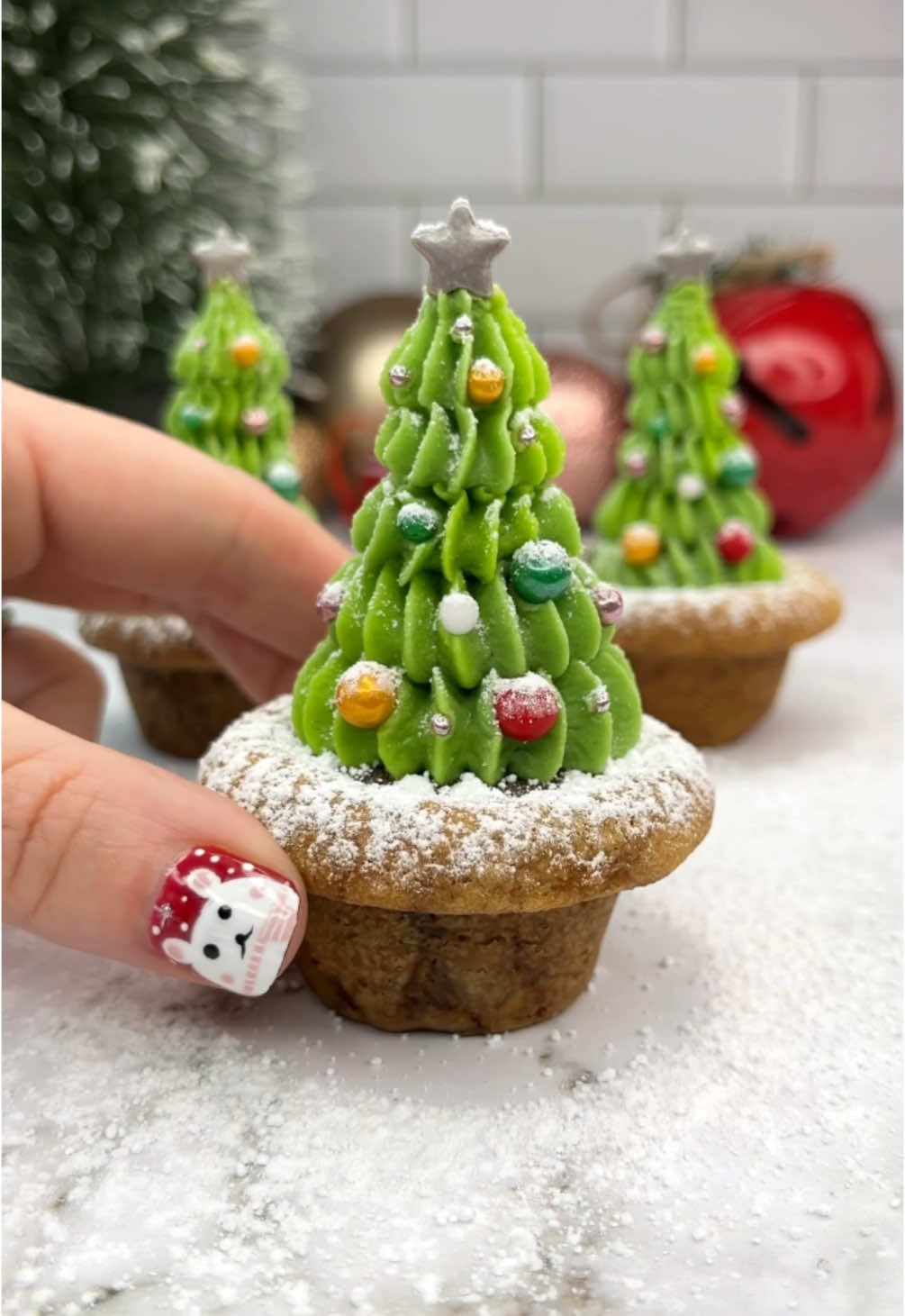 Christmas tree cookie pots 🎄🍪🪴 Day 23 of 24 days of Christmas treats 🎅🏼🧁🍪 I used store bought cookie dough for these and they work great 👌🏻  🍪 Add 28g dough balls into a greased mini muffin tin. 🎄Make an indent in the centre of each one using the back of a measuring spoon.  🍪 Bake for 20 minutes, until the edges are golden. (Time depends on oven temp🌡️ mine was 160C fan)  🎄 Remove from the oven and press the indent again, while still hot. Let them cool.  🍪 Fill the centres with a little melted milk chocolate. Add a half of a pocky stick into the middle and let it set in place.  🎄 Use piping tips 8B and 4B to add the green buttercream trees.  ❤️ Decorate with sprinkles and dust with powdered sugar:  #christmastree #christmasbaking #cookiepots #cakedbyrach #christmascountdown #christmasbaking #EasyRecipe #cutefood #christmastiktok 