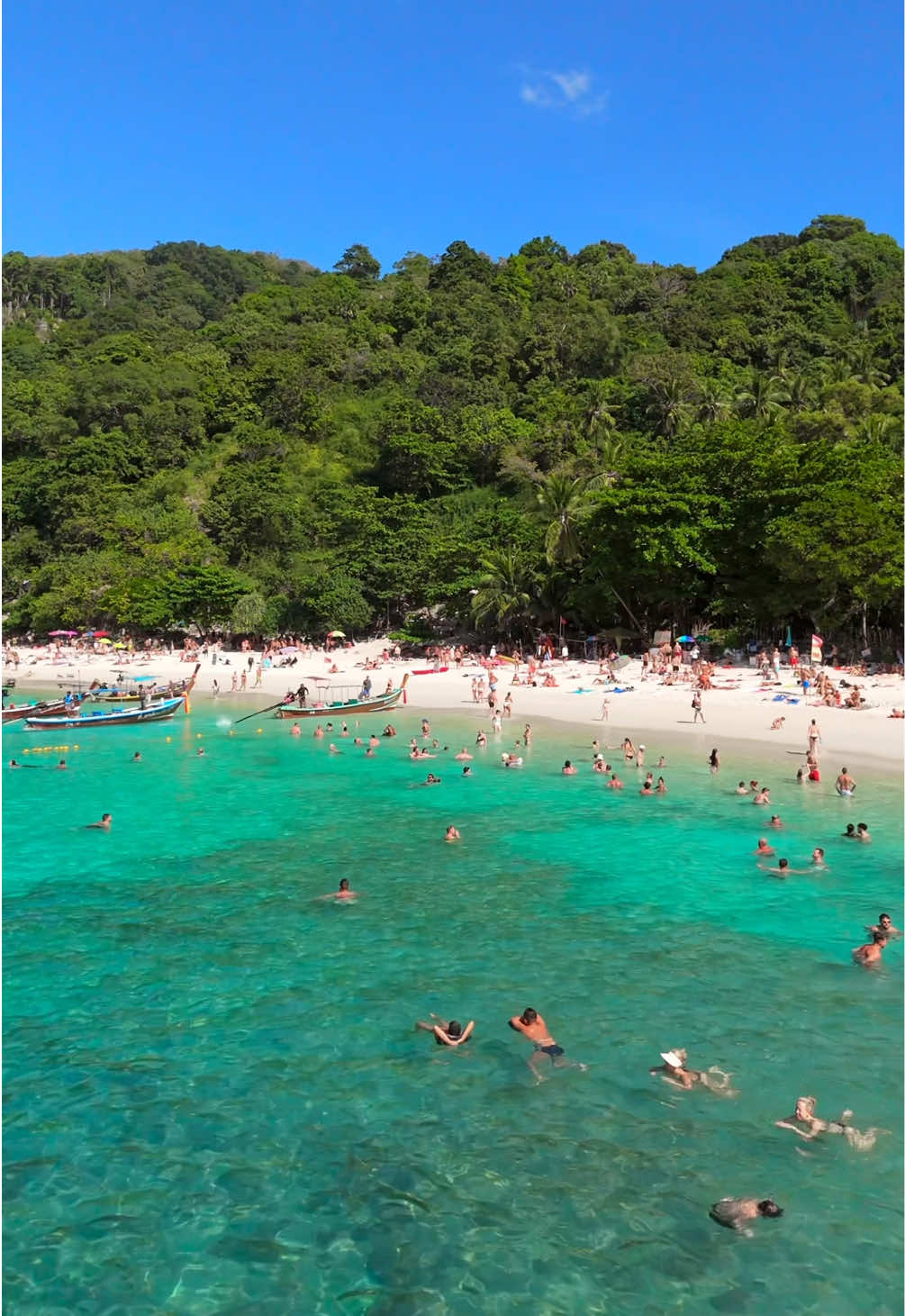 Peak high season at Freedom Beach in Phuket brings vivid turquoise waters, soft sands, and a tropical setting framed by lush hills. Popular with visitors, it buzzes with activity as people enjoy the clear, waveless sea and vibrant tropical vibe. #freedombeach #phuket #phuketbeach #thailand #fyp #foryou 