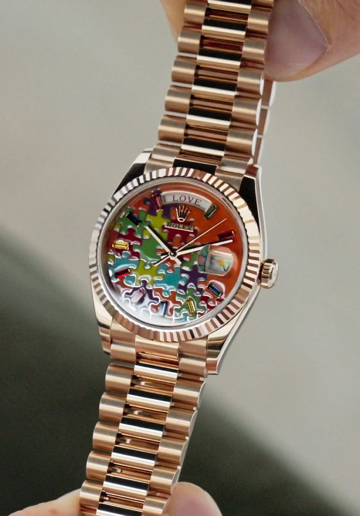Looking back at the unique features of the extremely fun and ridiculously rare off-catalogue Rolex Day-Date 36 “Puzzle” in rose gold. An unexpected yet joyful release back in 2023, and available in three variants (rose gold, yellow gold and white gold), it’s safe to say no one expected this from Rolex. Widely different to a traditional Day-Date, the day aperture at the 12 o’clock position contains seven phrases, “Happy”, “Eternity”, “Gratitude”, “Peace”, “Faith”, “Love” and “Hope”, whilst the date aperture at the 3 o’clock position has 31 different emojis in place of the date. As well as these two quirky features, the dial itself is a mesmerising piece of art. Entirely crafted through champlevé enamelling, the depth and detail of the dial is truly breathtaking. Turquoise blue, red, fuchsia, orange, green, and yellow jigsaw pieces fit together to make for an incredibly lively dial. Topped off with 10 baguette-cut sapphires in six different hues set according to the main colour of the dial, which in this rose gold variant is orange, the craftsmanship is exceptional. Should you be interested in this particular reference, or anything similar, please do not hesitate to reach out. #Rolex #DayDate #DayDate36 #Puzzle #PuzzleDial #128235 #DayDatePuzzle #watches #luxury #watchesoftiktok #fyp #watchtok #mensfashion #foryou #menswatches #style #watchoftheday 