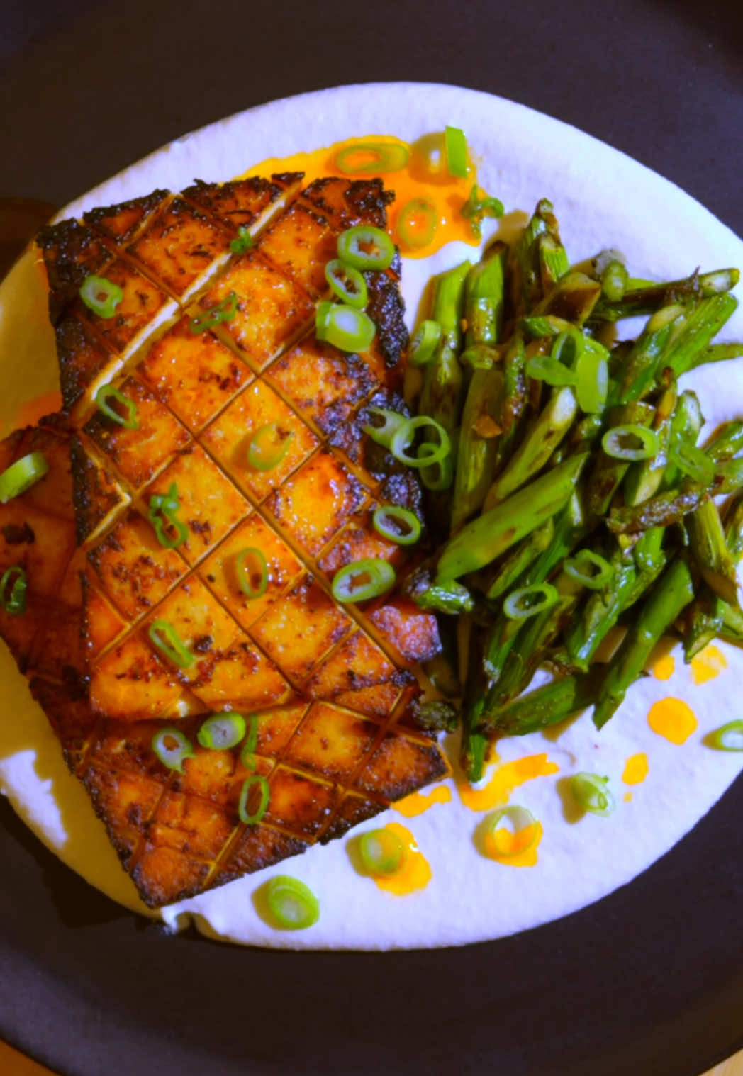 LEMON-GARLIC TOFU W/ CHARRED ASPARAGUS & MISO CASHEW CREAM 🔥  full recipe below ⬇️  ok, first off, this was SO tasty. like, how did this go so well?? I figured the ingredients would work together, but I was blown away by the final flavor and texture. an absolute must try for an upcoming weeknight dinner  spring is on the way and asparagus coming into season. I wanted to use it in a simple dinner recipe that still gives you bold flavor and texture. this one delivered beyond expectations. in every bite, you get charred asparagus paired with crispy-meaty tofu and velvety cashew cream. this is was so bomb, and now I’m hungry again. enjoy, my friends 🙏🏼 #veganrecipes #tofu #asparagus  Full recipe here!: ingredients salt, pepper, & olive oil (as specified) 1 block super firm tofu, cut into 4 planks, each scored on one side 1/4 cup soy sauce 1 tablespoon maple syrup 1 tablespoon chili crisp oil 4-5 cloves garlic, grated 2 lemons, juiced separately 1 1/2 cups (220g) whole cashews 2 cups plus 1 cup boiling hot water 2 tablespoons (30g) white miso 1 bunch asparagus spears, ends removed, cut on the bias into 1-inch pieces scallions and chili oil for garnish prep add the tofu slices to a glass storage container. In a large bowl, whisk together the soy sauce, maple syrup, chili crisp oil, juice of one lemon, garlic paste, and 1/2 tap ground black pepper. Four over the tofu in the storage container, place a lid on, and allow to marinate 30 mins (you can move the container every so often to make sure the tofu is evenly covered. While the tofu marinates, combine the cashews with 2 cups hot water and let sit 15 mins. Strain the cashews and add to a blender with the miso paste, juice of the other lemon, 1/4 tsp salt, and 1 cup hot water. blitz until creamy smooth. You can also prep the asparagus into 1 inch pieces at this point. Remove the tofu from the marinade and sear in a cast-iron pan over medium high heat until crispy golden brown with charred edges, about 4 to 5 mins per side. Remove the tofu and add the asparagus to the pan, cooking down another 2 to 3 mins. Serve the tofu and asparagus over a bed of cashew cream and finish with chili crisp oil and freshly sliced scallions.