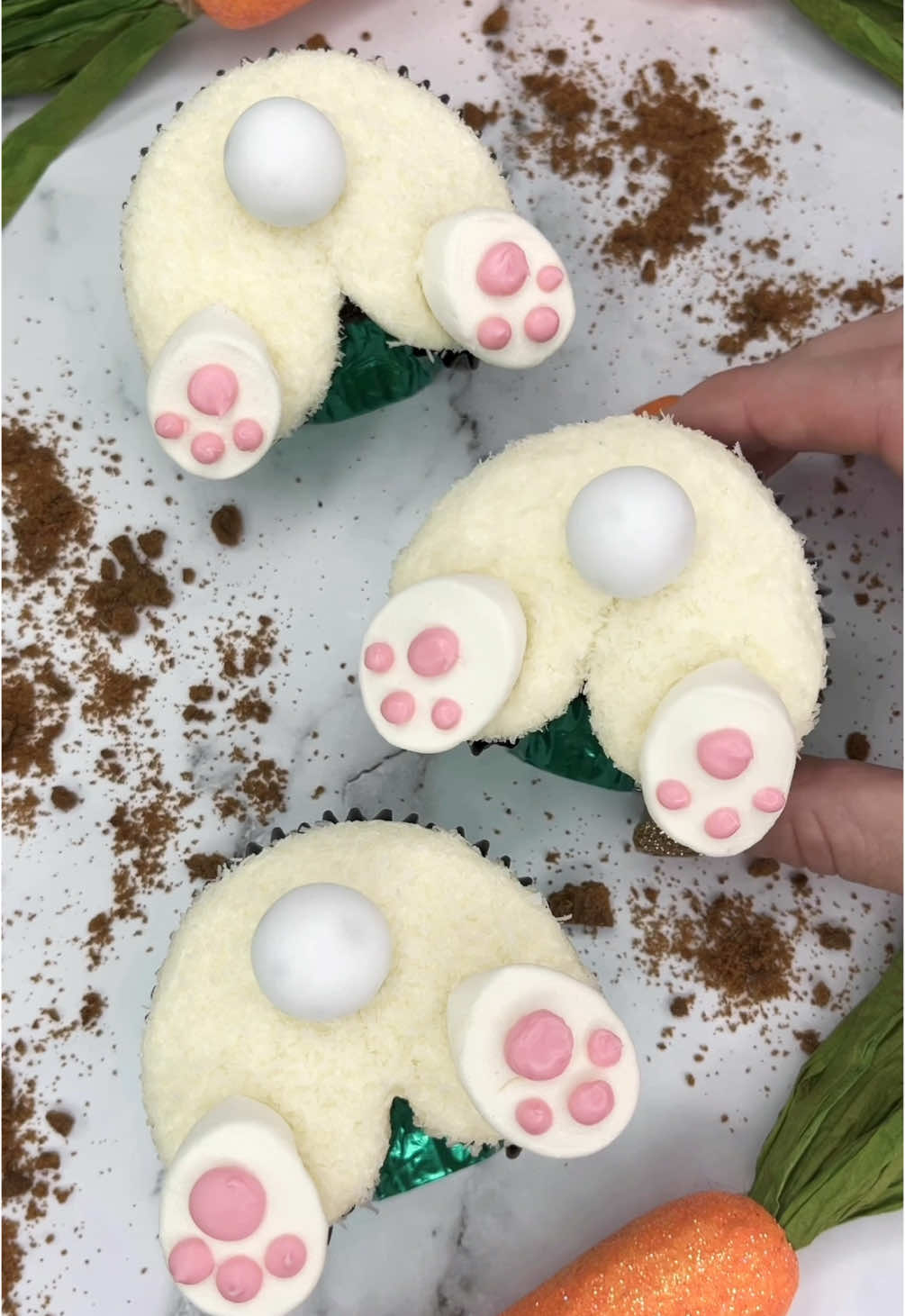 🐰Turning cupcakes into… Bunny butts 🐰 My most popular design from last Easter🐰🐣and they are in my new book too 🧁📕🐰 #cupcakesforanyoccasion  🐰 Fill your liners half full.  Use marbles or foil balls to shape your liners. 🐰 Bake and cool. 🐰 Use tip 1A to pipe buttercream in the shape of a bunny butt 🐰🩷 🐰 Press into desiccated coconut 🥥 🐰 Cut marshmallows in half for the feet and pink candy melts for the pads 💗 🐰 I used white chocolate balls for the tail  #cupcake #bunnybutt #easterbaking #cutebaking #cakedecorating #cakedbyrach #cupcakesforanyoccasion   