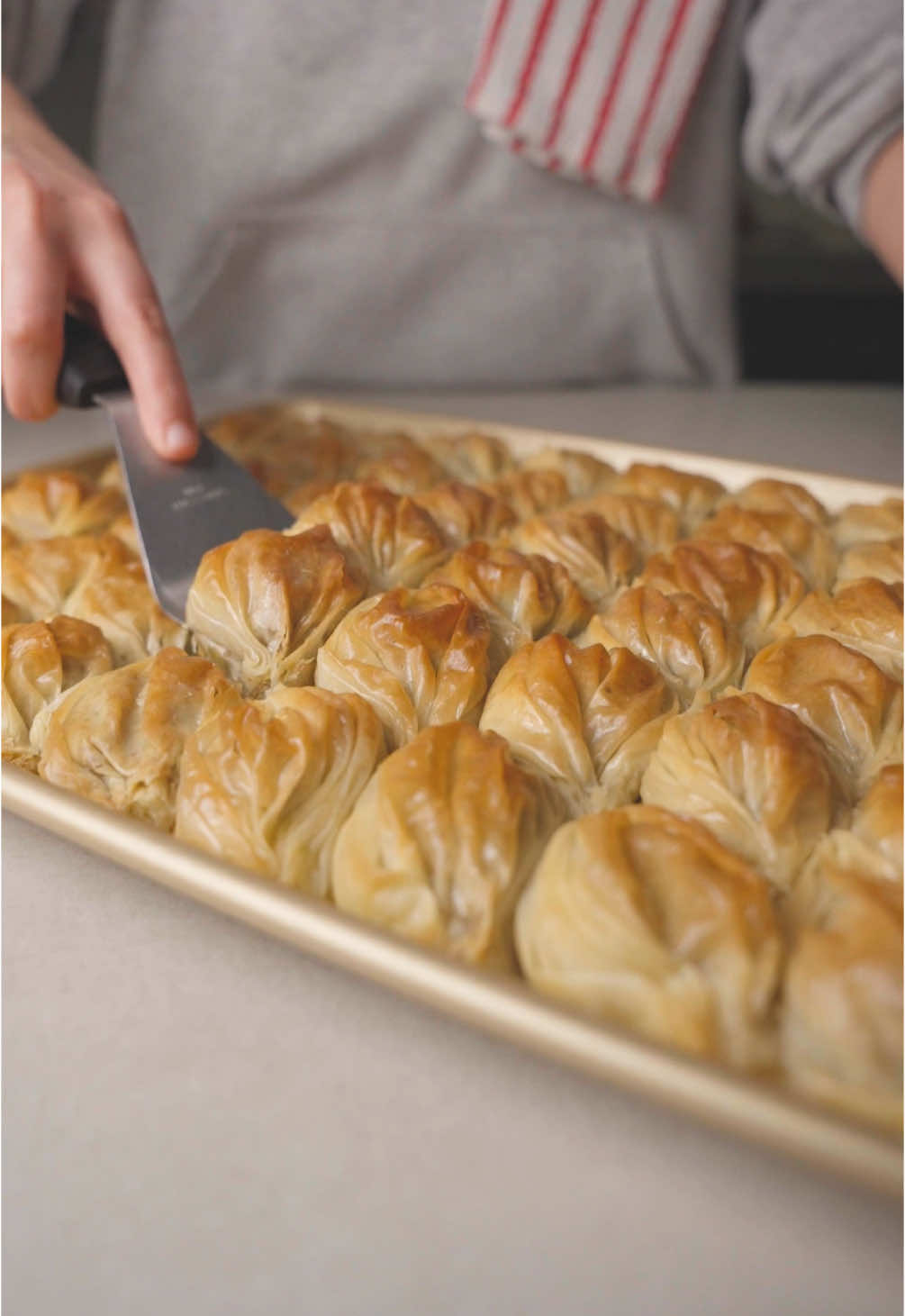 Eid Mubarak! Turkish #baklava with pistachio 🥠  #toomacooks #ramadan2025 #tiktokcookbook  Ingredients | المكونات: 2 rolls frozen filo pastry (thawed) | رولان من عجينة الفيلو المجمدة (مذوبة) 500g pistachios (finely chopped) | 500 غرام فستق حلبي مفروم ناعم 200g ghee (melted) + more as needed | 200 غرام سمن مذاب + كمية إضافية حسب الحاجة Sugar syrup (cold) | قطر بارد Instructions | طريقة التحضير: Preheat Oven to 180°C (350°F). سخن الفرن على حرارة 180 درجة مئوية. Prepare the Baklava as shown in the video, layering the filo pastry with pistachios. قم بتشكيل البقلاوة كما هو موضح في الفيديو، مع وضع طبقات من عجينة الفيلو والفستق الحلبي. Brush with Ghee generously to ensure crispiness. ادهن السمن المذاب بسخاء لضمان القرمشة. Bake for 20–30 minutes or until golden brown. اخبز لمدة 20 إلى 30 دقيقة أو حتى يصبح اللون ذهبياً. Pour Cold Syrup over the hot baklava immediately after baking. اسكب القطر البارد فوق البقلاوة الساخنة فور إخراجها من الفرن. Let it Soak before serving. اتركها لتمتص القطر قبل التقديم.