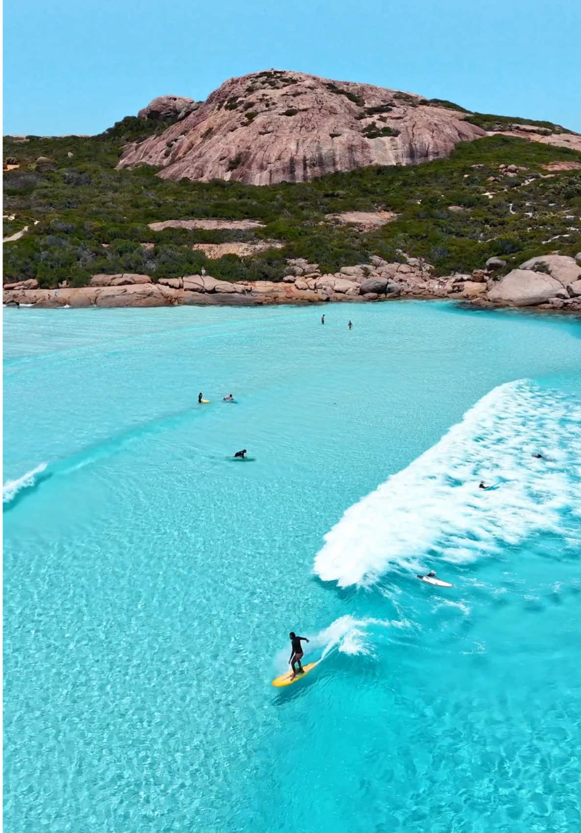 Surf's up in Western Australia 🏄 The glassy waves of Wharton Beach make for stunning scenes and even better surfing conditions, backed by dramatic rocky cliffs for postcard-worthy moments. Stay in nearby Kepa Kurl (@visitesperance) to enjoy beach days on repeat 👌 🎥: @Christie & Josh  📍: Wharton Beach, @Australia’s Golden Outback, @Western Australia  #SeeAustralia #ComeAndSayGday #WATheDreamState #AustraliasGoldenOutback ID: Aerial view over a group of surfers riding clear, glassy waves in the ocean beside a rocky headland sprinkled with greenery.