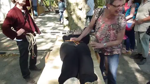 Girl in strapped to the table at a local french renfaire.  She has her arms tied above her head and her feet in sandals locked in the pillory.  Her feet and toes are poked then her shoes are taken off while everyone cheers while the tickling begins.    She struggles to break free as her soles are tickled.