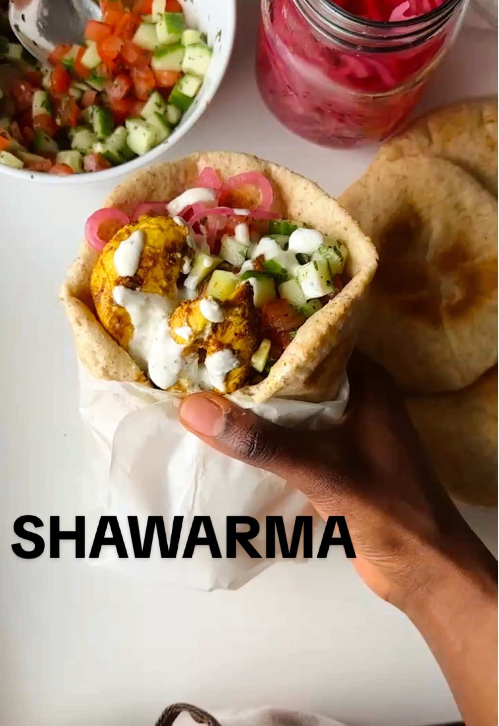 we’re in.. the Middle East I guess! (so many countries eat shawarma idk which to choose lol) 🥙❤️ Pita Bread - 8 small pitas / 4 large  - 2 teaspoons instant yeast or quick-rising yeast  - 2 tablespoons olive oil + more for brushing  - 1 cup warm water + a bit more if needed  - 1.5 teaspoons salt - 2.5 cups flour, spooned and leveled (equal parts all-purpose white & whole wheat)  - more flour for rolling  Chicken  - 1 chicken breast, sliced thinly - 2 tbsp cup full fat yogurt  - 1 tbsp olive oil - 1/2 a lemon juice  - 1 clove garlic, minced - 1 tsp ground cumin - 1/2 tsp ground paprika  - 1/2 tsp ground turmeric - 1/2 tsp ground allspice - 1/4 tsp ground black pepper - 1/2 tsp salt  - 1/4 tsp cayenne - olive oil, for pan to cook Creamy garlic sauce  - 2 tablespoons labneh  - 1 tbsp olive oil  - 2 tbsp Greek yogurt  - juice of 1/2 a lemon  - 1 garlic, minced  - salt & pepper  Garnish  - pickled onions  - cucumbers & tomatoes, diced w/ salt & lemon juice  In a bowl, mix flour, instant yeast & salt. Stir in olive oil & warm water a bit at a time. I used a hand mixer with dough hooks and added a very bit more l water because whole wheat flour absorbs more water. On a floured surface, knead for 7-10 minutes with your hands or in a stand mixer (with dough hooks) on med-low speed for 7 minutes. Once dough is smooth, form into a large ball & brush with olive oil. Place in a bowl, cover with a damp cloth & allow to rise in a warm place (like your oven that’s off) for 1.5hrs.  Combine all chicken marinade ingredients in a bowl & coat chicken pieces. Cover & allow to marinade for 1hr (overnight is best though!). Once dough has doubled, punch out the air & on floured surface, roll into a rope. Divide into equal balls - I did 4 small & 2 large, then cover with damp towel to rest for 10-15min. Preheat oven to 500F with a sheet pan inside & the rack on the bottom. Combine all garlic sauce ingredients together, whisking vigorously to mix well then set aside. In a pan with some olive oil, cook your chicken strips over med heat for 3-4min each side depending on thickness.  Roll out pita balls on a floured surface, add to sheet pan & bake for 3-4 min until they puff, turning & baking for another 1-2 min - all depending on size of pitas too! Longer times for bigger pieces. Place pitas in a kitchen towel before serving, to keep steam & warmth.  Once ready, allow to cool & assemble with chicken, garnishes & creamy garlic sauce!  #fyp #healthyrecipes #simplehighproteinrecipes #pita #pitabreadrecipe #shawarma #shawarmarecipe #middleeast #middleeasternfood #middleeasternrecipes #chickenshawarma #FoodTok #foodgram  