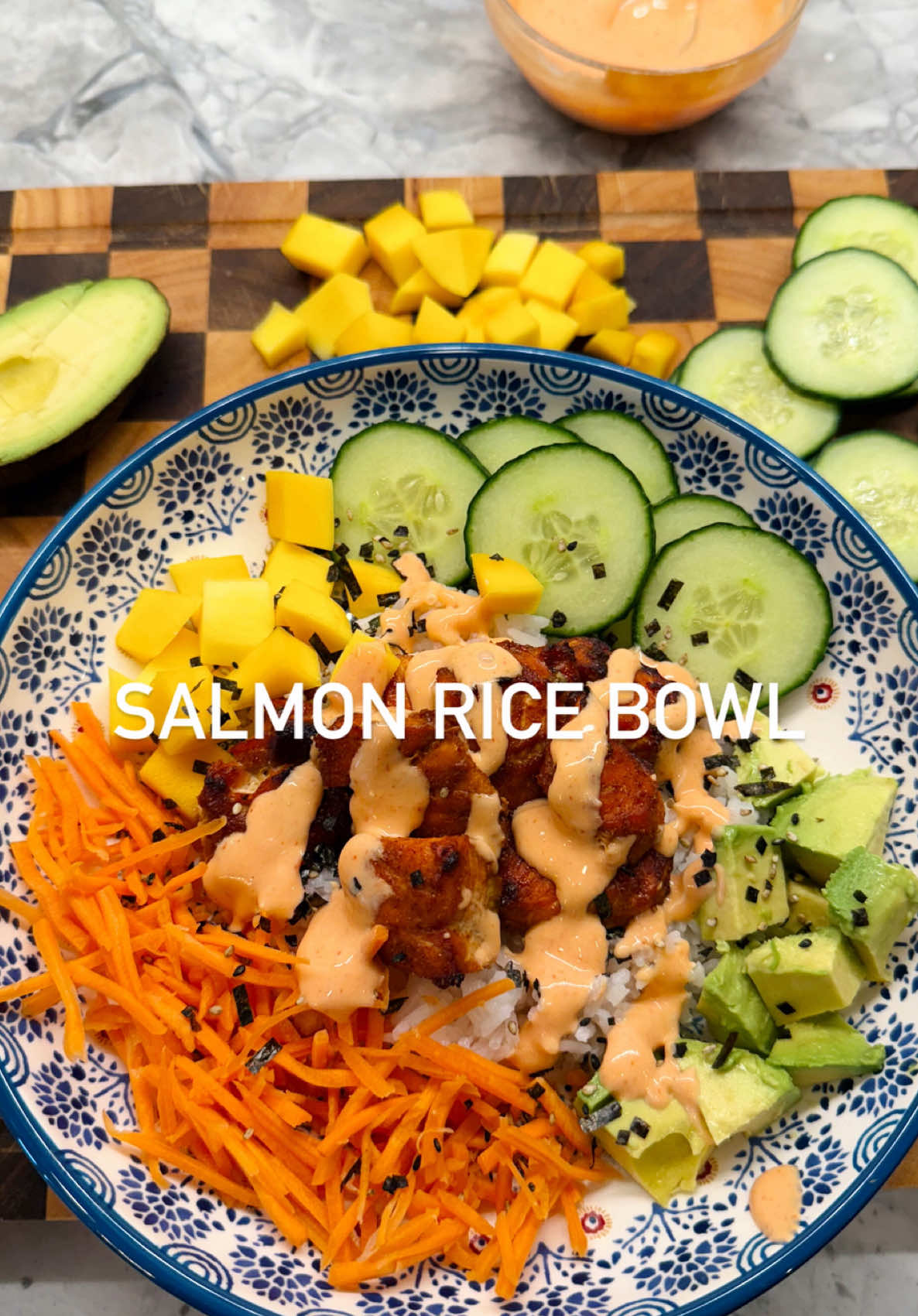 Easy high protein salmon bowls! Perfect to meal prep for lunch to help fuel your day🍣🩷 RECIPE: 1 wild caught alaska salmon filet, skin removed 1/2 mango, diced 1/4 cup cucumber, thinly sliced 1/4 cup carrots, shredded  1 half avocado, diced 1/2 cup Basmati rice or quinoa, pre-cooked  1/2 avocado  Dash of furikake on top  For the Salmon Seasoning:  2 tablespoons coconut aminos  1 teaspoon garlic powder  1/2 teaspoon smoked paprika  1/2 teaspoon chili flakes  1 1/2 teaspoon hot honey  Pinch of salt and pepper For the spicy yogurt sauce 1/2 cup plain greek yogurt 1 teaspoon sesame oil 2-4 tablespoons sriracha  1 teaspoon hot honey Pinch of salt and pepper DIRECTIONS -Chop the salmon into 1 inch cubes and place into a bowl. Season the salmon and let the salmon marinate in the fridge for 20-30 minutes before cooking. Place in the air fryer at 390 degrees for 10 to 12 minutes. -Meanwhile dice the mango, slice your cucumber, dice avocado, and shred your carrots.  -Make your spicy yogurt sauce and set to the side. Add more or less sriracha depending on your spice tolerance.  -To serve, add your cooked rice, add a dash of furikake on top, then place the cooked salmon on top. Add your mango, avocado, sliced carrots, and cucumbers on the side circling around the rice. Top the salmon off with that spicy yogurt and enjoy! 