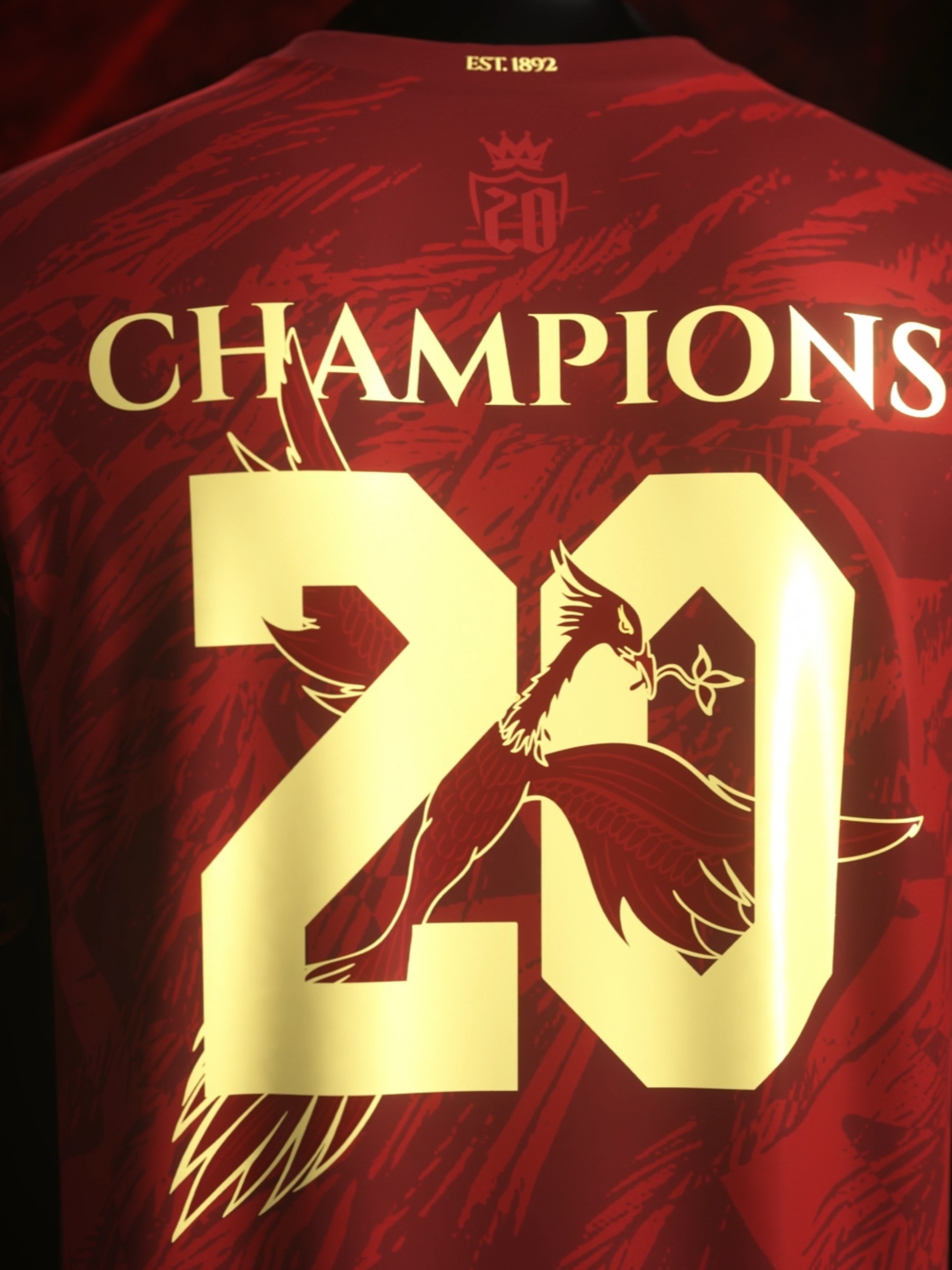 Introducing The Reds Away Jersey. Your 2025 English Champions - AVAILABLE NOW. A highly requested red edition of our bestselling The Reds Jersey. Featuring the Shankly Gates streaking down the sides in gold, and the mythical liverbird flying through #20. All on a deep red checkered feather-inspired base. Available now for pre-order.