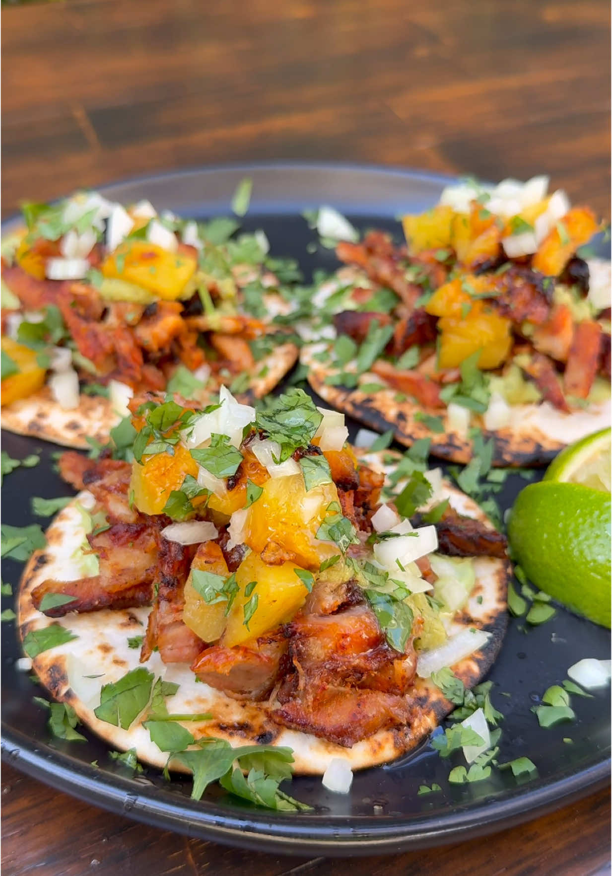 AL PASTOR TACOS on the Rotisserie 🔥🐖🔥 Nothing better than shaved pork off the JoeTisserie, with grilled pineapple, a smoky tomatillo-poblano salsa, and avocado crema! 😋 WHAT YOU NEED: • 6-8lbs pork shoulder (thin sliced) • 1 whole pineapple (cut 2 thick chunks for the spit, dice after cooking) • 1 small white onion, diced • Corn tortillas • Chopped cilantro, lime wedges ⸻ MARINADE (Adobo): • 8–10 dried guajillo chiles • 4 dried ancho chiles • 6 garlic cloves • 1/2 cup white vinegar • 1/2 cup OJ • 2 chipotles in adobo (optional) • 2 tbsp achiote paste • 2 tbsp Mexican oregano • 2 tsp cumin • 2 tsp black pepper • 2 tsp salt • 1 tsp cinnamon • 4 tbsp brown sugar • 2 tsp Blazing Starr Reaper Rub Toast chiles, soak in hot water 10 min, blend everything into a smooth marinade. ⸻ MARINATE IT: Coat pork slices in marinade. Chill min 4 hrs or overnight. ⸻ STACK IT: Skewer 1 pineapple chunk → stack pork → top with 2nd pineapple chunk. Secure tight. ⸻ SPIN IT: Set Kamado Joe to 350F. Spin on JoeTisserie 1.5–2 hrs. As outer pork chars, shave it off, let the next layer keep cooking. Repeat for juicy, caramelized layers. ⸻ DICE THE PINEAPPLE: Remove grilled chunks, dice ’em up — that’s your sweet taco topper. ⸻ MAKE THESE SAUCES: Roasted Tomatillo Salsa: • 4–5 tomatillos • 2 poblanos • 1 jalapeño • 1/2 white onion • 3 garlic cloves • 1/4 cup cilantro • Juice of 3 limes • Salt & pepper Roast Peppers & Tomatillos. Blend everything. Avocado Crema: • 2 avocados • 1/2 cup sour cream • Juice of 3 limes • 1 garlic clove • 1/4 cup cilantro • Salt & pepper Blend until smooth. ⸻ BUILD YOUR TACOS: Warm tortilla → avocado crema → shaved pork → diced grilled pineapple → roasted tomatillo salsa → chopped onion + cilantro → squeeze of lime. ⸻ 🔥 Tag someone who needs to try this #KamadoJoe #JoeTisserie #AlPastor #BBQtacos #smokenvine #teamred #tacos #tacotuesday🌮 #cincodemayo #alpastortacos #bbq #delicious #foodporn #reels #yum #mexicanfood #streettaco #taco #homecooking #rotisserie #pineapple #sogood #letsgo #yum #tacosalpastor #delicious  . . . @Kamado Joe @blazingstarbbq @blazingstarshop @Swift Meats @HexClad @blendtec @waringproducts @foodandwine @Food Network @Foodies @Foodie @Foodporn @FOOD 🍟 @Gordon Ramsay @Jealous Devil @AMF 