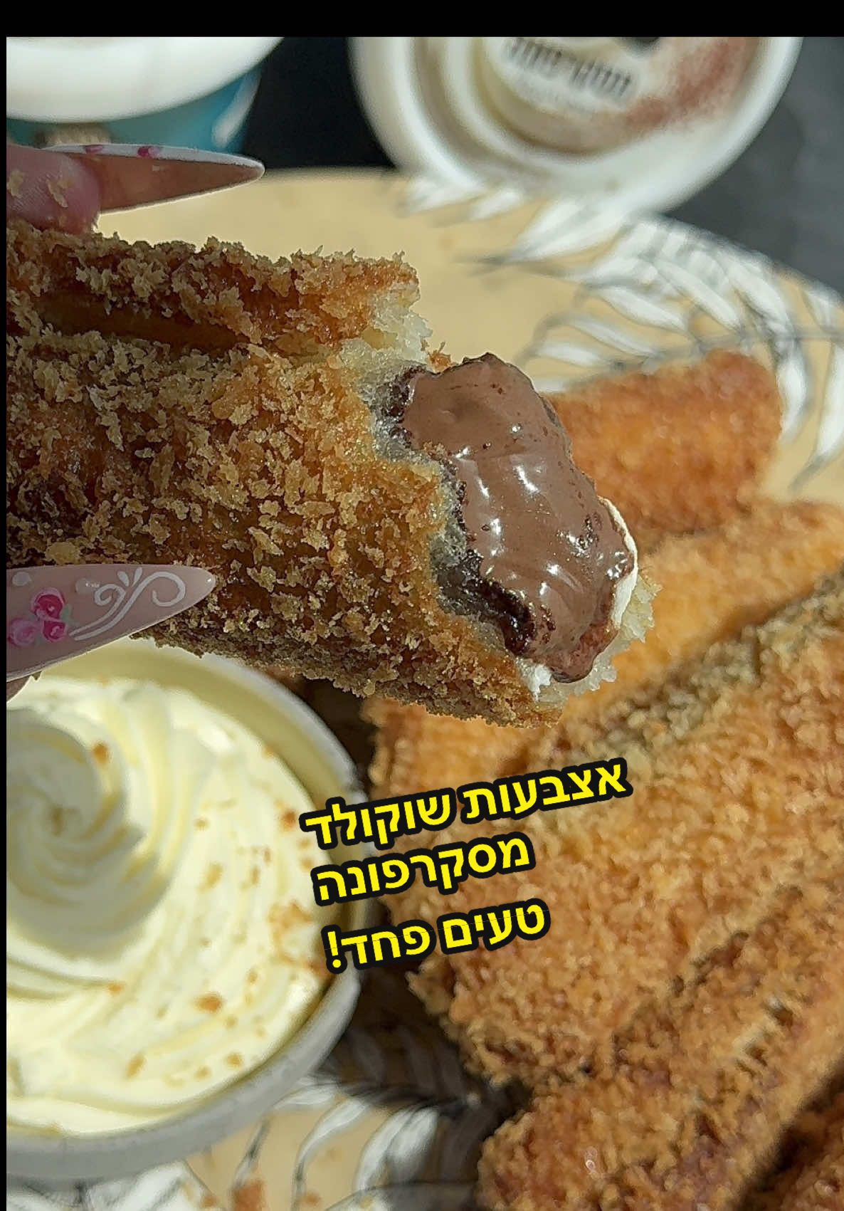 פרסום ממומן בשיתוף @tara_milk  אצבעות מסקרפונה שוקולד חמותתתת עם קרם מסקרפונה שוקולד לבן חלום. על פניו זו יכולה להראות מנה מלוחה- ואז מגיעה ההפתעה. מבחינתי מסקרפונה זה חומר גלם שמעיף למעלה גם מנות מלוחות וגם מתוקות והמסקרפונה של טרה מדהימה! מרקם חלום!  מצרכים: 10 פרוסות לחם לבן בלי הקשה  1 מיכל מסקרפונה של טרה  1 כוס ממרח שוקולד שאוהבים לסגירה: 1/4 כוס קמח לבן 1/2 כוס מים  לציפוי וטיגון: 3 ביצים 2 כוסות פנקו  1-2 ליטר שמן (לפי גודל הסיר/מחבת) לקרם מסקרפונה שוקולד לבן: 50 גרם שוקולד לבן מומס 50 גרם מסקרפונה של טרה  אופן הכנה: 1. חותכים את הקשה של הלחם (או קונים לחם בלי קשה😅) 2. מרדדים כל פרוסת לחם עם מערוך עד שהיא דקה מאוד 3. מעבירים את המסקרפונה לשקית זילוף, וגם את ממרח השוקולד לשקית זילוף  4. מניחים על פרוסת הלחם פס מסקרפונה, ופס ממרח שוקולד (בתחילת הפרוסה).  5. מערבבים את חומר ההדבקה שלנו- קמח ומים.  6. מורחים על המסגרת של הפרוסה את הקמח והמים שערבבנו  7. מגלגלים לרולדה הדוקה וחשוב לסגור טוב טוב שלא יפתח בטיגון. 8. מכינים קערה עם ביצים מקושקשות, וקערה עם פנקו  9. טובלים כל אצבע כזאת בביצה, ואז בפנקו. 10. מכינים מחבת רחבה ועמוקה עם שמן עד 1/2 גובה מהמחבת. מחממים את השמן ל170-180 מעלות (אם אין מד טמפ אז זה טמפ בינונית) 11. מטגנים כל אצבע כזו עד הזהבה יפה מכל הכיוונים. מעבירים לרשת צינון  12. לקרם מסקרפונה שוקולד לבן: ממיסים במיקרוגל שוקולד לבן, אם מפחדים שישרף אפשר להוסיף כף שמן ואז להמיס במיקרוגל. 13. מערבבים את השוקולד המומס עם המסקרפונה עד למרקם של קרם- אוכלים באותו רגע עם האצבעות שוקולד מסקרפונה החמות כי אח״כ הקרם מתקשה! נשבעת לכם שתברכו אותי.