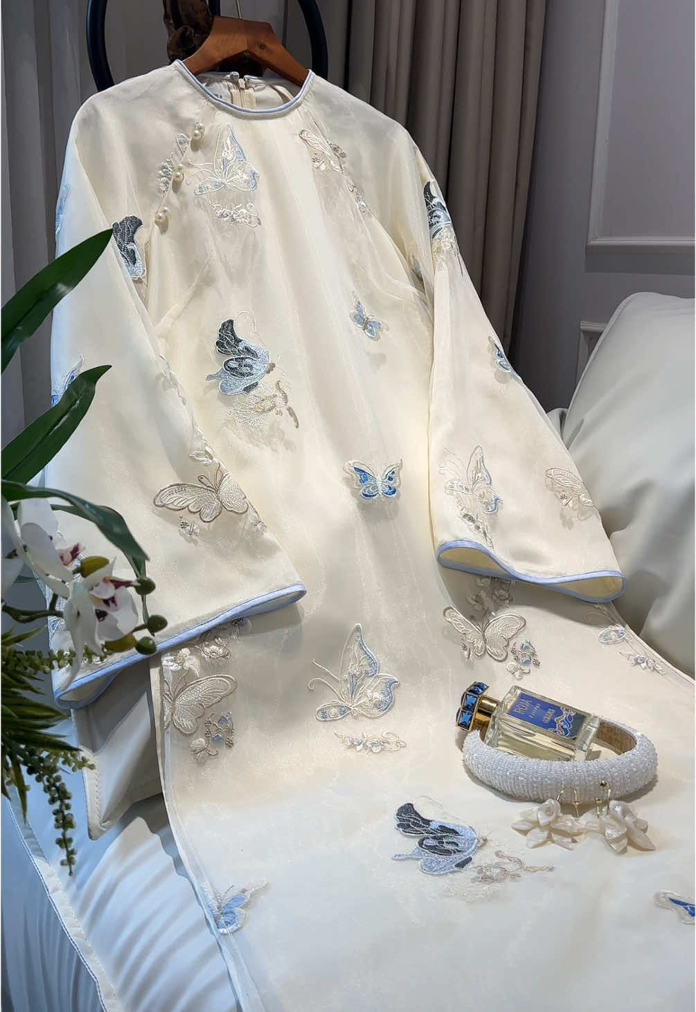 Chất liệu tơ thêu được sử dụng trong các mẫu áo dài là loại tơ cao cấp, mềm mại, có độ óng ánh nhẹ dưới ánh sáng, giúp tôn lên vẻ sang trọng và thanh thoát cho người mặc. Bề mặt vải mịn, thoáng nhẹ, tạo cảm giác dễ chịu khi mặc trong thời gian dài. Các chi tiết thêu thủ công từ cánh bướm, hoa nhỏ đến các họa tiết tròn cổ truyền đều được thực hiện tỉ mỉ bằng chỉ tơ và chỉ ánh kim, tạo chiều sâu và độ nổi cho từng họa tiết.  #aodai #áodài #aodaiedini #ÁoDàiTruyềnThống #aodaihottrend #vietnam #aodaicuoi #aodaivietnam #edini #aodaitruyenthong 