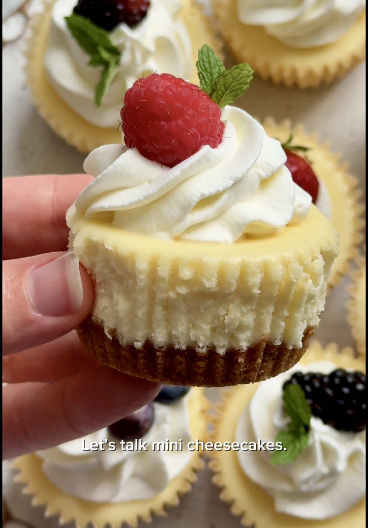 Individual Cheesecakes 🍓🫐🍒 Recipe is below and link in my bio for the full website recipe with more topping options, instructions for super mini cheesecakes, and freezing details 😁 ⠀⠀⠀⠀⠀⠀⠀⠀⠀ Makes 12 CRUST -1 cup (120g) graham cracker crumbs (about 8 graham crackers) -2 Tbsp (25g) granulated sugar 3 Tbsp (43g) unsalted butter, melted FILLING 16 ounces (452g) full-fat brick cream cheese, softened 1/2 cup (100g) granulated sugar 1/4 cup (60g) sour cream, at room temp 1 tsp pure vanilla extract 1 tsp freshly squeezed lemon juice 2 large eggs, at room temp ⠀⠀⠀⠀⠀⠀⠀⠀⠀ 1.  Preheat oven to 350°F (177°C). Line a 12-count muffin pan with liners. 2.  Combine all of the crust ingredients. Mixture will be sandy. Firmly press a heaping Tablespoon of crust mixture into each liner. Bake for 6 minutes. 3.  Make the filling: Using a mixer fitted with a paddle or whisk attachment, beat the cream cheese and sugar together on medium-high speed until the mixture is smooth and creamy, about 2 minutes. Add the sour cream, lemon juice, and vanilla, and beat until fully combined. With the mixer running on medium, add the eggs 1 at a time, beating just until combined before adding the next. Do not over-mix. Divide the batter among the liners, filling each all the way to the top. (It's OK if the crust is still warm.) 4.  Optional Water Bath (prevents cheesecakes from excess sinking): Boil a pot of water. Place a large pan (do not use glass) on the bottom oven rack of the preheated oven. Pour boiling water into pan, about 1 inch deep. Immediately place the cheesecakes on the center rack. 5.  Bake until the edges are set and the centers slightly jiggle when you tap the pan, about 20 minutes. 6.  Set the pan on a cooling rack and allow cheesecakes to cool at room temperature for 45 minutes, then transfer to the refrigerator and chill for at least 2 hours and up to 24 hours. 7.  Top the cheesecakes with optional toppings. I used Wilton 1M tip for piping fresh whipped cream.
