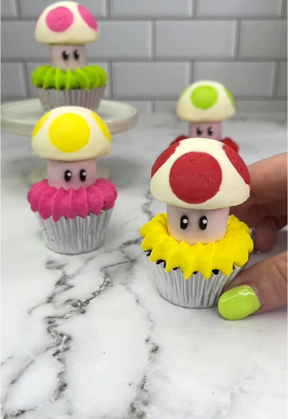 Buttercream Toads 🍄 I used a silicone cake pop mold to make these cuties 🍄 you could also use a sphere ice cube mold  🍄 Pipe coloured buttercream dots into your silicone mold 🍄 FREEZE 🥶 for 15 minutes 🍄 Add white buttercream into the mold, followed by your pink marshmallows  🍄 FREEZE 🥶 again for 15 minutes. 🍄 Push them out of the mold and keep them in the fridge until you’re ready to use 🍄 👀 I used black buttercream and mini white sprinkles for the eyes.  😆 Sit your toads on top of mini cupcakes ✨ VOILA 🩷💛💚❤️ #cupcakes #toad #supermario #cakedbyrach #cakeart #cupcakedecorating #cutecake #cutecupcakes #toad #cupcakesforanyoccasion 