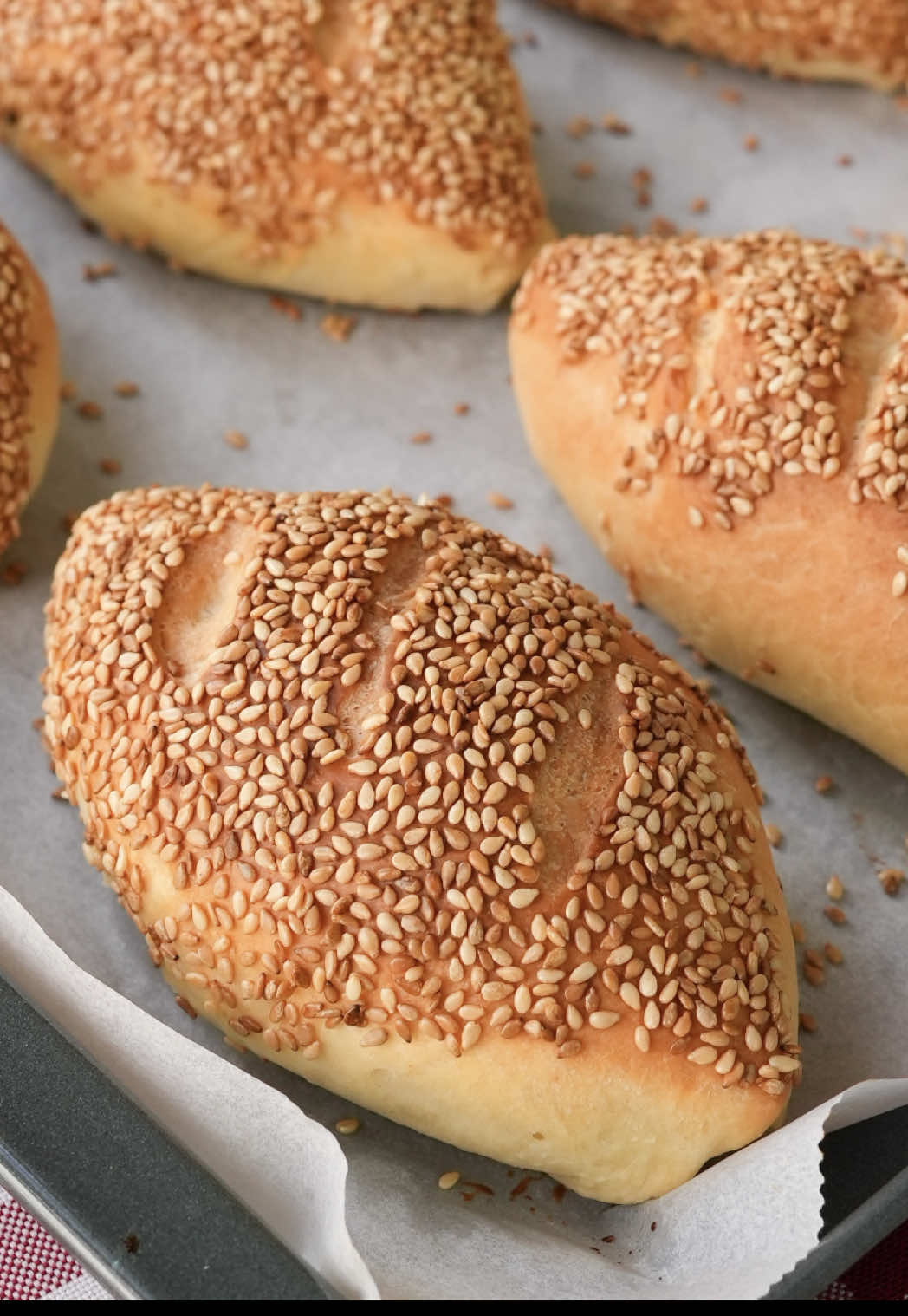 Simit Poğaça 😋 Bu poğaçaların dışı çıtır çıtır susam kaplı, içi ise yumuşacık ve peynirle dolu! 😍 Kaydetmeden geçmeyin. 😉 Simit Poğaça Malzemeler 1 su bardağı ılık süt (200 ml) 1 paket instant maya 2 adet yumurta Yarım su bardağı sıvı yağ (100 ml) 1 tatlı kaşığı mahlep 2 tatlı kaşığı şeker 1 tatlı kaşığı tuz 4 su bardağı un İçi için; 150 g kaşar peyniri 100 g beyaz peynir Dışı için; Yarım su bardağı su 2 yemek kaşığı pekmez Kavrulmuş susam Hazırlanışı Öncelikle yoğurma kabına maya, şeker ve ılık sütü alarak karıştıralım. Sıvı yağ, yumurtalar, tuz ve mahlebi ekleyerek karıştırmaya devam edelim. Son olarak yavaş yavaş unu ekleyelim ve hamuru yoğurmaya başlayalım. Ele yapışmayan yumuşak bir kıvam alan hamuru toparlayalım ve üzerini önce streç film ile ardından temiz bir örtü ile örterek 40 dakika mayalanmaya bırakalım. Mayalanan hamurun üzerini açıp havasını aldıktan sonra, hamuru tezgahta 12 eşit parçaya bölelim. Kolaylık olması için hamuru önce 4 parçaya, sonra her birini 3’e kesebilirsiniz. Kestiğimiz parçaları elimizle yuvarlayarak beze haline getirelim. Hazırladığımız bezeleri bastırarak biraz genişletelim. Ortalarına kaşar peyniri ya da beyaz peynir yerleştirip kenarlarından tutarak ortada birleştirelim ve kapatarak poğaça şeklini verelim. Sıkıca kapatmaya dikkat edelim ki pişerken açılmasın. Tüm bezeleri aynı şekilde hazırladıktan sonra, uygun bir kapta su ve pekmezi karıştıralım. Poğaçaları önce bu pekmezli suya, ardından bolca kavrulmuş susama bulayalım. Hazırladığımız poğaçaları pişirme kağıdı serdiğimiz fırın tepsisine dizelim. Ben bu ölçülerle 12 adet poğaça elde ettim. Üzerlerine bir bıçakla, çok derin olmayacak şekilde çizikler atalım. Poğaçaların üzerini temiz bir örtüyle kapatıp 20 dakika kadar tepsi mayasında bekletelim. İyice kabaran poğaçaları önceden 180 dereceye ısıttığımız fırında, fansız ayarda 25 dakika pişirelim. Puf puf yumuşacık simit poğaçalarımız servise hazır. Afiyet olsun! #nefisyemektarifleri #nefis #tarif #bugünnepişirsem #poğaça #simitpoğaça #tiktokmutfağı 