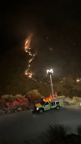 In this image, flames stretch like bleeding tears from the heart of the mountain, quietly consuming the trees and plants, while the civil defense vehicle stands at the bottom of the scene as a silent witness to a voiceless tragedy