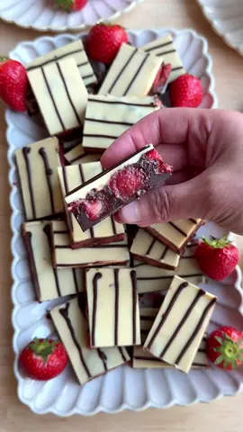 STRAWBERRY CHOCOLATE BARS #food #recipe #foryou #fyp #chocolate #strawberries #bars #dessert BASE 150 g milk chocolate FILLING 150 g dark chocolate 100 ml heavy cream 400 g strawberries TOPPING 175 g white chocolate 25 g dark chocolate Melt the milk chocolate (150 g) using a bain-marie (double boiler). Heat the heavy cream (100 ml) in a small saucepan until it’s almost boiling. Remove from the heat and add the dark chocolate (150 g) in pieces. Let sit for 1 minute, then stir until smooth. Cut the strawberries (400 g) into pieces and place them in a bowl. Add the chocolate ganache and mix until well combined. Pour the melted milk chocolate into a baking dish and spread it evenly over the base. Spread the strawberry mixture evenly on top. Place in the refrigerator and let it set completely (at least 1 hour). Melt the white chocolate (175 g) using a bain-marie. Pour the melted white chocolate over the chilled filling. Melt the dark chocolate (25 g) using a bain-marie and pour into a piping bag. Pipe thin lines over the white chocolate. Freeze for at least 1–2 hours to fully set. Cut into pieces and serve.