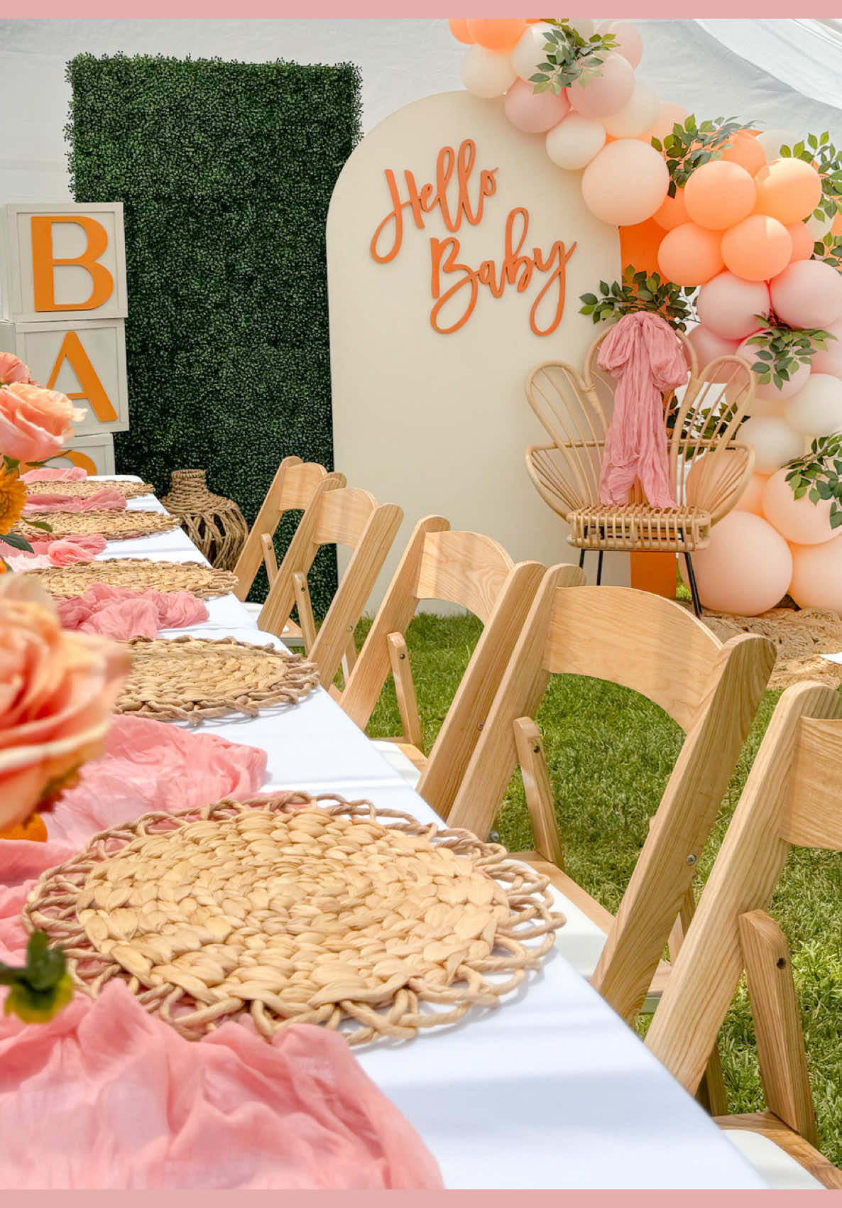 softening the sunlight over peach, orange, and cream hues.  Natural chairs stand gracefully among elegant tables, setting the perfect stage for this baby shower. Ready to book your next unforgettable moment? #backdropdecoration #alittlecutieisontheway #babyshowerideas #gardenbabyshower #hellobaby 