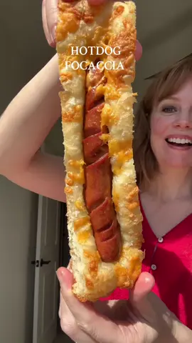 Hear me out: HOTDOG FOCACCIA 🌭  Way better than any bun you can buy from the store! The crunch, the floof, the flavor! This is my new go to way to make hotdogs! 🤗 What are your favorite toppings??  #Recipe  2 cups bread flour (272 grams) 1 ⅛ tsp instant dry yeast (about half a packet, or 3.5 grams) 1 tsp salt (6 grams) 1 tsp honey (7 grams) 1 cup warm water (about 105°F) (236 grams) 1 tbsp extra virgin olive oil (13.5 grams), plus more for pan and kneading 5 long beef hotdogs Cheddar cheese, shredded, (optional) What to do: 1. Place flours, yeast, salt, honey and olive oil mix in a large bowl. Pour in warm water and mix with a wooden spoon. Once the flour is wet, let the mix sit for about 10 minutes. Mix again until dough comes together and flour disappears. Wet your hands and begin kneading the dough. I pull one chunk of dough up above the bowl, stretch it then wrap it around the rest of the dough. Turn the bowl 45 degrees. I repeat this about 8-10 times. Cover the dough with a towel, repeat this process after 15 minutes. Then, cover the Focaccia, and let it sit for about 90 minutes. The focaccia should roughly double in size. 2. Using 1 tbsp of olive oil, grease a  13x9 (shallow, like a baking sheet) pan. Place your focaccia dough into the pan. Spread gently with your fingers. Cover the dough with another pan of equal or greater size (the dough needs room to rise). Let the dough rise in a warm place for another 90 min. To make the spiral hotdogs, place a dog on a skewer. On a cutting board, spin the skewer, using a sharp knife, pierce the dog as you spin. You should work in a vertical fashion, top to bottom.  Remove dog from the skewer and set to the side.  3. Preheat oven to 450. Pour about 1 tbsp of olive oil on the focaccia. Using your hands, press down into the dough, creating dimples. Evenly spaced 5 hotdogs. Sprinkle the focaccia with cheese, if desired!  4. Bake for about 20-25 minutes at 450 degrees. Focaccia should be hard to the touch and golden brown on the outside. Cool, slice and serve with all your hotdog fixins! I used mustard and pickle de gallo from grillos!  Insp: @The Food In My Beard  . . #hotdog #summerrecipes #focaccia #baking #baketok #fyp  