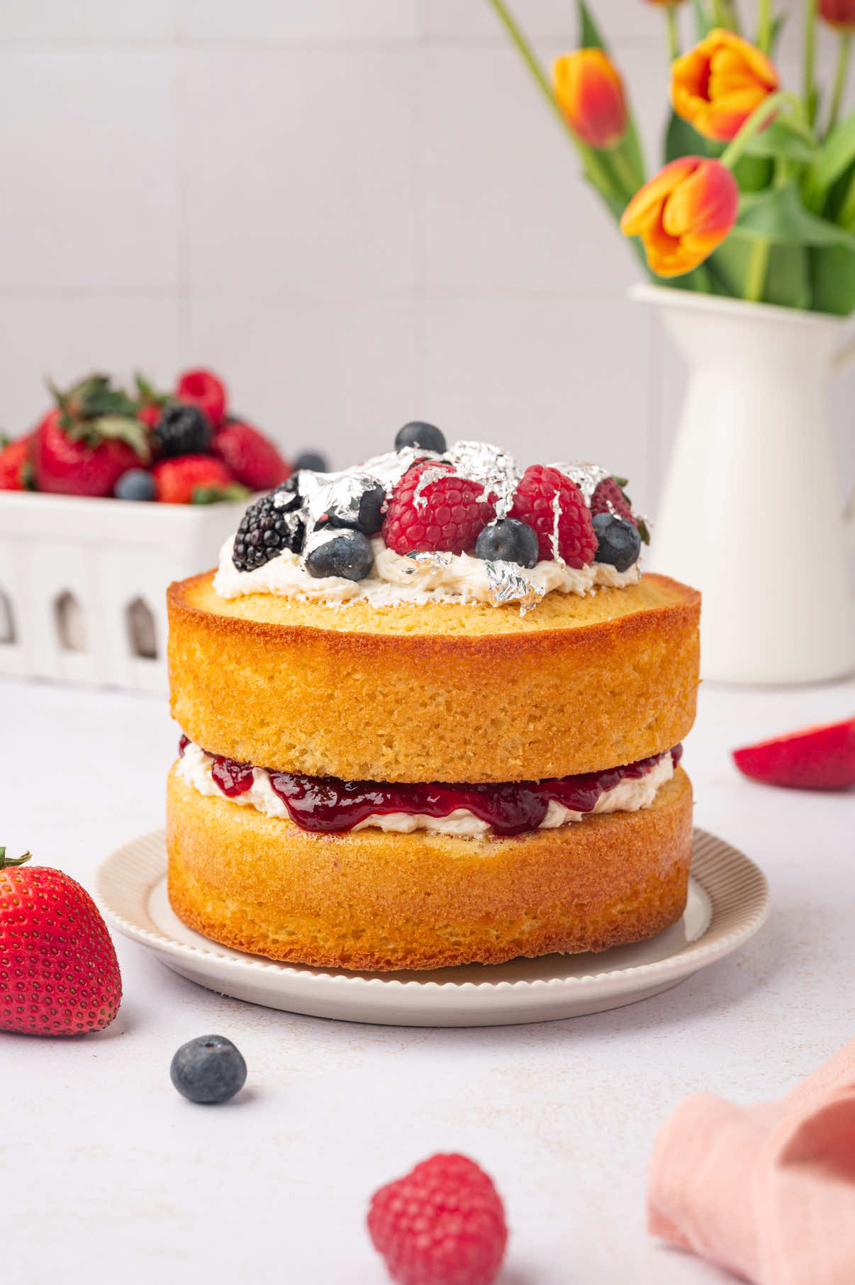 Ingredients
 For the sponge cake
 1 ½ cups all-purpose flour
 1 teaspoon baking powder
 ⅛ teaspoon salt
 ¾ cup unsalted butter, at room temperature
 1 cup granulated sugar
 4 large eggs, at room temperature
 2 teaspoons vanilla extract 
 For the filling
 ½ cup butter
 1 ½ cups confectioners sugar
 ½ teaspoon vanilla
 ⅓ cup raspberry spread
 1 cup mixed fresh berries, to decorate
 Edible silver leaf, to decorate
 Fresh mint leaves, to garnish 
 Directions
 1. Preheat your oven to 350°F. Grease two 6-inch round pans with oil, cover with parchment paper, and set aside.
 2. In a medium bowl, whisk together the flour, baking powder, and salt. Set aside.
 3. In a large bowl, beat the butter and sugar on medium speed using a hand mixer for 3-5 minutes until pale and light.
 4. Gradually add the eggs, one at a time, mixing thoroughly after each addition. Add the vanilla extract and mix well.
 5. Sift the flour mixture into the wet ingredients and mix until everything comes together. Divide the batter evenly between the two prepared round pans.
 6. Bake in the preheated oven for 18-20 minutes, or until a toothpick inserted into the center of the cakes comes out clean. Remove the cakes from the oven and allow them to cool in the pans for 5 minutes before transferring to a wire rack to 
 cool completely. 7. Meanwhile, prepare the filling by beating the softened butter and confectioners' sugar together until smooth and creamy. Add the vanilla extract and mix until the filling is smooth.
 8. To decorate the cake, place one cake layer on a serving plate and top with 3/4 of the filling, spreading it evenly. Spread the raspberry spread over the filling and top with the second cake layer.
 9. Spread the remaining filling on top of the second cake. Arrange the fresh berries on top of the filling and garnish with edible silver leaf and mint.
 10.Slice and serve the cake to enjoy.