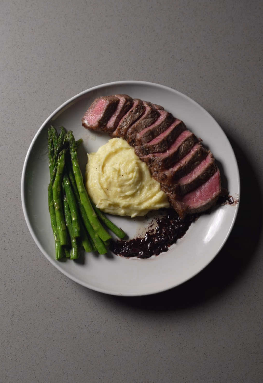 who wants a plate?  We’ve got a beautiful New York strip with red wine reduction, Truffle mashed potatoes & garlic butter asparagus. Another perfect date night dinner  📖 Recipe  °Ingredients° Steak: •2 New York strips (6-8 oz each, about 2 inches deep) •salt & freshly cracked black pepper  •2 tbs oil  •3 tbs butter •6-8 garlic cloves (crushed. You know I love me some garlic) •rosemary  Red wine reduction: •1 shallot (finely minced) •1 cup red wine (I used Cabernet Sauvignon) •1/2 cup beef stock  •1 tbs butter  •salt to taste Truffle mashed potatoes: •1lb Yukon gold potatoes  •1/3 cup heavy cream  •6 tbs butter •1-2 tbs truffle oil (start small) •1 tsp salt  •1/2 tsp garlic powder  •1/2 tsp black pepper  Garlic butter asparagus: •2 tbs butter •3 garlic cloves (crushed)  •drizzle of olive oil  •salt & pepper to taste   °Instructions° Mashed potatoes: •cut and boil potatoes until soft. Mash the potatoes and stir in heavy cream, butter, truffle oil & seasonings. Stir until smooth and creamy Steak: •Bring steak to room temp. Season all sides generously with salt & pepper. Heat your pan on medium high heat  •Sear steaks for 2-3 minutes per side. Once turned over, add butter, garlic and herbs. Tilt pan and baste steaks for another 1-2 minutes  •Rest steaks for 5-10 minutes, tent in foil to keep warm  Red wine reduction sauce: •in the same pan, remove excess fat but keep brown bits  •sauté shallots until soft (1-2 min) •add wine, bring to a boil, then reduce heat by half  •add beef stock, simmer until thickened (about 10 minutes) •whisk in cold butter for silkiness, season to taste Asparagus:  •trim ends, sauté in olive oil and butter with garlic cloves for 4-5 minutes, until tender-crisp. Season with salt and pepper #steak #steakdinner #truffle #mashedpotatoes #EasyRecipe #datenight 