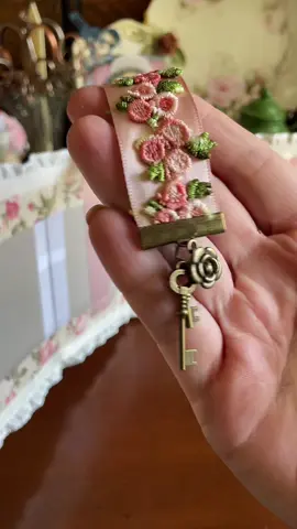 Getting the bookmark added onto my journal cover. Some ribbon, extra trim, a metal end clamp, a few charms, and it’s good to go!🌹😁🗝️ #bookmark #handmade #BookTok #journal #thevintagejournal #tutorial #craft #crafting #journaling #craftsupplies #vintage #roses #asmr #vibes  