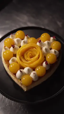 Soft in the middle. Sweet on the lips #mangoseason #passionfruitcheesecake Tropical, golden, and impossible to resist. This baked mango & passionfruit cheesecake has a buttery macadamia base, a golden mango-infused cheesecake, and layers of passionfruit jelly. Topped with silky white chocolate crémeux, mango jelly spheres, and a hand-carved mango rose in the shape of a heart. Recipe’s live in my subscriber group  #bakedcheesecake #homemadedessert #summerfruits 