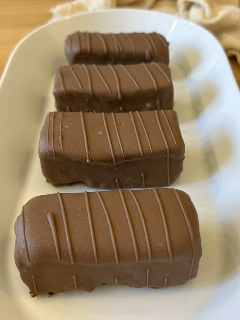 חטיף טעמי ביתי 🍫 8-10 יחידות - לבסיס: 80 גרם פצפוצי אורז 50 גרם שוקולד מריר/חלב/לבן 75 גרם חמאה 200 גרם נוטלה/ממרח שוקולד אחר - לקרמל: 120 גרם סוכר 120 מ״ל שמנת מתוקה 25 גרם חמאה קורט מלח גס - לציפוי: 250 גרם שוקולד חלב 25 גרם חמאת קקאו/שמן  - אופן ההכנה: מתחילים עם הבסיס -  בקערה שמים חמאה, שוקולד מריר ונוטלה וממיסים בפולסים במיקרו עד לקבלת תערובת אחידה (30 שניות אמור להספיק, חשוב להיזהר לא לשרוף את השוקולד) מוסיפים את פצפוצי האורז ומערבבים לאיחוד. מסדרים ברינג/תבנית אינגליש קייק בצורה אחידה. מכניסים בנתיים להתייצבות במקפיא. - מכינים את הקרמל - בסיר קטן/מחבת שמים סוכר ומחממים על אש בינונית/גבוהה עד שהסוכר מתקרמל (להיזהר לא לשרוף אותו) במקביל בסיר נפרד מביאים שמנת לסף רתיחה. כשהסוכר הופך לצבע חום ענברי מנמיכים את האש ללהבה הכי נמוכה וטורפים בהדרגה את השמנת לקרמל. אחרי הוספה של כל השמנת וקבלת קרמל אחיד מכבים את האש, מוסיפים חמאה ומלח וטורפים לאיחוד. נותנים לקרמל להתייצב 10 דקות בטמפרטורת החדר ולאחר מכן שופכים אותו מעל תחתית פצפוצי האורז והשוקולד ומיישרים בצורה אחידה. מעבירים למקפיא לחצי שעה. - מצפים - בקערה שמים שוקולד חלב וחמאת קקאו/שמן וממיסים בפולסים במיקרו עד לקבלת תערובת אחידה. מחלצים את הבסיס עם הקרמל מהרינג/תבנית, חותכים למלבנים בגודל שרוצים וטובלים כל מלבן בשוקולד. מניחים על תבנית עם נייר אפייה ומעבירים למקפיא להתייצבות נוספת (עד שהציפוי מתקשה לגמרי) עם השוקולד שנשאר אפשר לקשט עם זילוף של פסים כמו שאני עשיתי *אחרי* שהציפוי של החטיפים מתקשה. שומרים את החטיפים במקרר  בתיאבון 🤍 #fyp #viral #פוריו #לומדים_עם_טיקטוק #טעמי #שוקולד #chocolate #snack #caramel #קרמל 