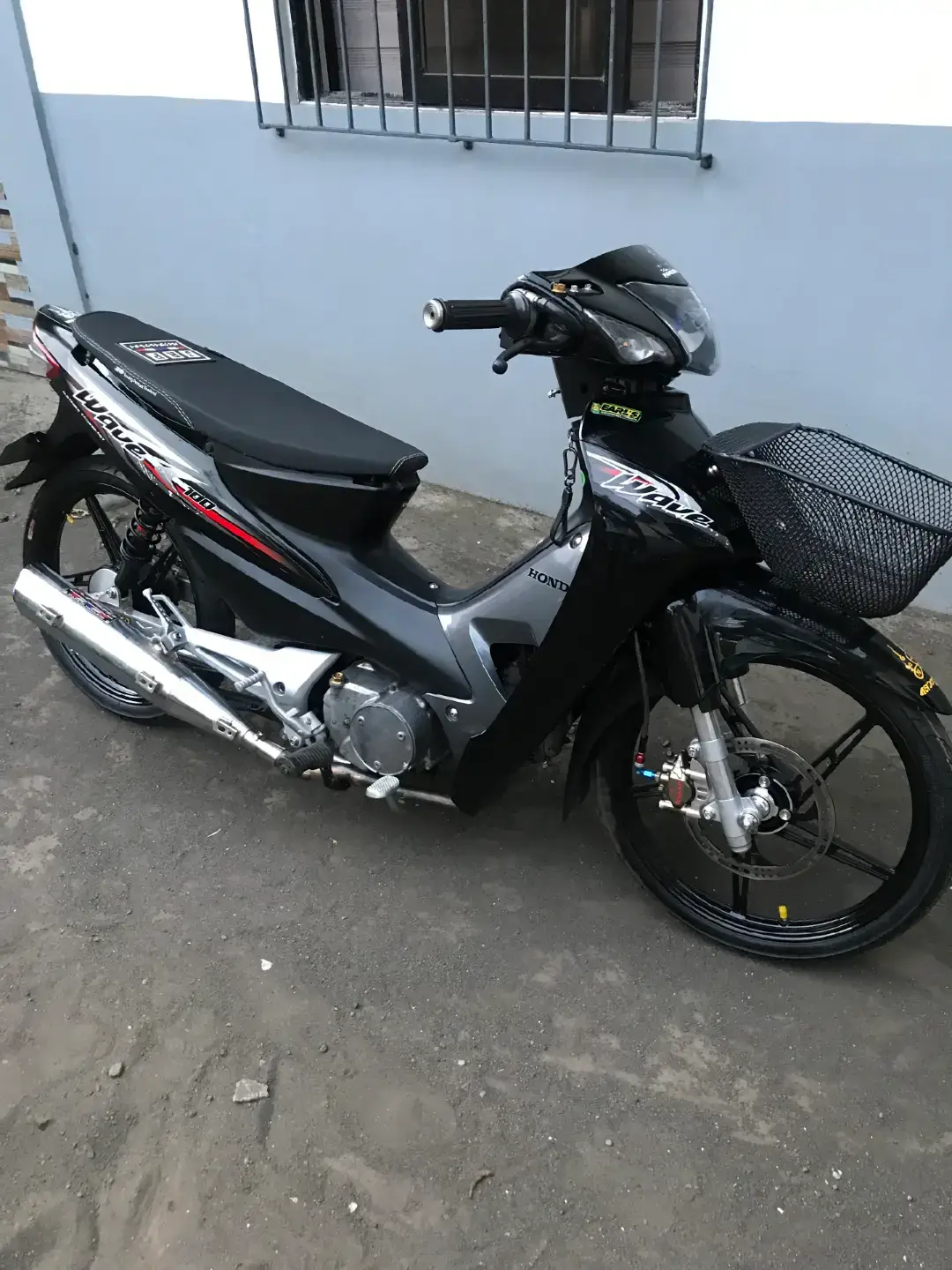 Here’s a clean and polished summary statement of the Honda Wave 100 specifications: Honda Wave 100 – Key Specifications Engine Type: Single-cylinder, 4-stroke, SOHC, air-cooled Displacement: ~97 cm³ (5.93 in³) Bore × Stroke: 50 × 49.5 mm Ignition: CDI (electronic) Fuel System: Carburetor (OHC)  Performance Power: ~7.2 HP (5.2 kW) @ ~8,000 RPM Torque: ~7.3 Nm (0.7 kgf·m) @ ~5,500 RPM  Top Speed: Often reported near 90–105 km/h depending on variant; not always officially specified  Transmission & Drive Gearbox: 4-speed semi-automatic (centrifugal clutch; no manual clutch lever) Final Drive: Belt (in most markets; older models may use chain)  Chassis & Suspension Frame: Steel underbone Front suspension: Telescopic fork Rear suspension: Twin shock absorbers  Brakes & Tires Brakes: Drum brakes front and rear (some markets offer front disc brake versions)  Tires (2014 spec): Front 70/90-17, Rear 80/90-17  Dimensions & Capacity Length × Width × Height: ~1,898 × 699 × 1,057 mm Wheelbase: ~1,234 mm Seat height: ~751 mm Ground clearance: ~133 mm Dry Weight: ~90–94 kg Fuel Tank Capacity: ~3.7 liters  The Honda Wave 100 features a reliable, air-cooled 97 cm³ SOHC engine delivering around 7.2 HP and 7.3 Nm of torque, paired with a user-friendly 4-speed semi-auto transmission and belt final drive. The compact underbone chassis, telescopic front fork, and twin rear shocks make it agile in urban traffic. With braking via drums front and rear (disc options in select markets), a fuel capacity around 3.7 L, and a lightweight design (~90–94 kg), it's both economical and practical for everyday riding.