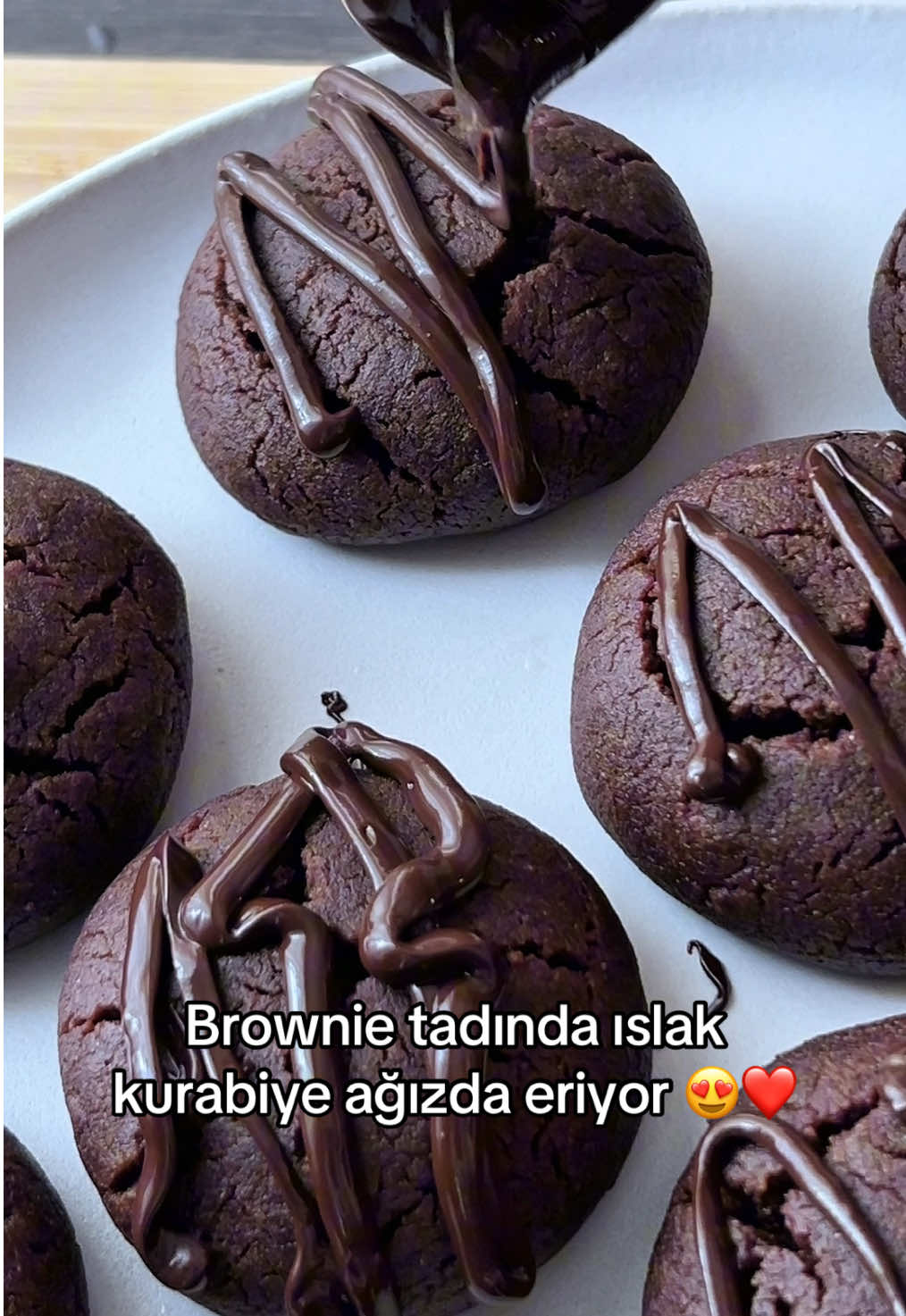 Süt Şerbetli Islak Kurabiye  Hamur için; 100 gr yumuşamış tereyağı 1 çay bardağı toz şeker 1 çay bardağı sıvıyağ 1 yumurta 3 su bardağı kadar un 1 paket vanilya 1 paket kabartma tozu 2 dolu yemek kaşığı kakao Şerbet için; 1 su bardağı toz şeker 2 su bardağı süt Üzeri için; Sütlü-bitter çikolatayı benmari usulü birlikte eritin. Sıkma torbası veya kaşıkla tatlıların üzerine dökebilirsiniz. Dilerseniz benim yaptığım gibi çok az da beyaz çikolata eritip minik minik zik zaklar yapabilirsiniz. Yapılışı: Önce şerbeti hazırlayın. Süt ve şekeri tencereye koyup ocağa alın. Şeker eriyene kadar ocakta kalması yeterli. Kaynamasına gerek yok. Ocaktan alıp soğumaya bırakın. Sonra hamuru hazırlamaya başlayın. Önce sıvı sonra kuru malzemeleri ekleyerek yumuşak bir hamur yoğurun. Hamuru istediğiniz gibi büyük veya küçük boylarda yuvarlayıp tepsiye dizin. Bu ölçüden ortalama 15-20 adet tatlı çıkarabilirsiniz. 180 derece fansız alt üst ayar ısınmış fırında kurabiyeler hafif çatlayana kadar pişirebilirsiniz. Fırından çıkıp bir kaç dakika dinlendikten sonra soğumuş süt şerbetiyle tatlıları buluşturabilirsiniz. Süt şerbetinde çok fazla durmamalı yoksa dağılır. Klasik bir tatlı gibi değil. Sadece biraz ıslanması yeterli. Kurabiyelerin ortasını şerbete batırmanız yeterli. Sonra servis tabağına nazikçe alın ve üzerini isterseniz sade bırakabilirsiniz. Fıstık veya hindistancevizi serpebilirsiniz veya benim yaptığım gibi çikolatayla tamamlayabilirsiniz. Deneyeceklere afiyet olsun. #ıslakkurabiye #kurabiye #kurabiyetarifi #tatlıtarifleri #tatlıkurabiye #çikolatalıkurabiye #ıslaktatlı #pratiktarifler #kolaytarifler #tarifler #tatlısaati #tatlısev #fırınsıztarifler #mutfaktayız #mutfakgram #evyapımıkurabiye #lezzetlitarifler #nefisyemektarifleri #şerbetlikurabiye #çikolatalıtatlı #brownie #fyppppppppppppppppppppppp #fypシ゚ #trendingsong #tiktokviral #kesfet #kesfetbeniöneçıkart #kesfetteyiz 