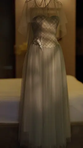 Aura — Where Moonlight Meets Elegance Draped in the softest whisper of slate blue, Aura captures the hush of twilight and the romance of a fleeting waltz. The corset bodice, traced with delicate check patterns and kissed by a single floral accent, flows effortlessly into cascades of airy tulle. A sheer, weightless cape drapes over the shoulders like moonlight on water — a final touch for the woman who embodies quiet luxury, timeless beauty, and the poetry of a night to remember.