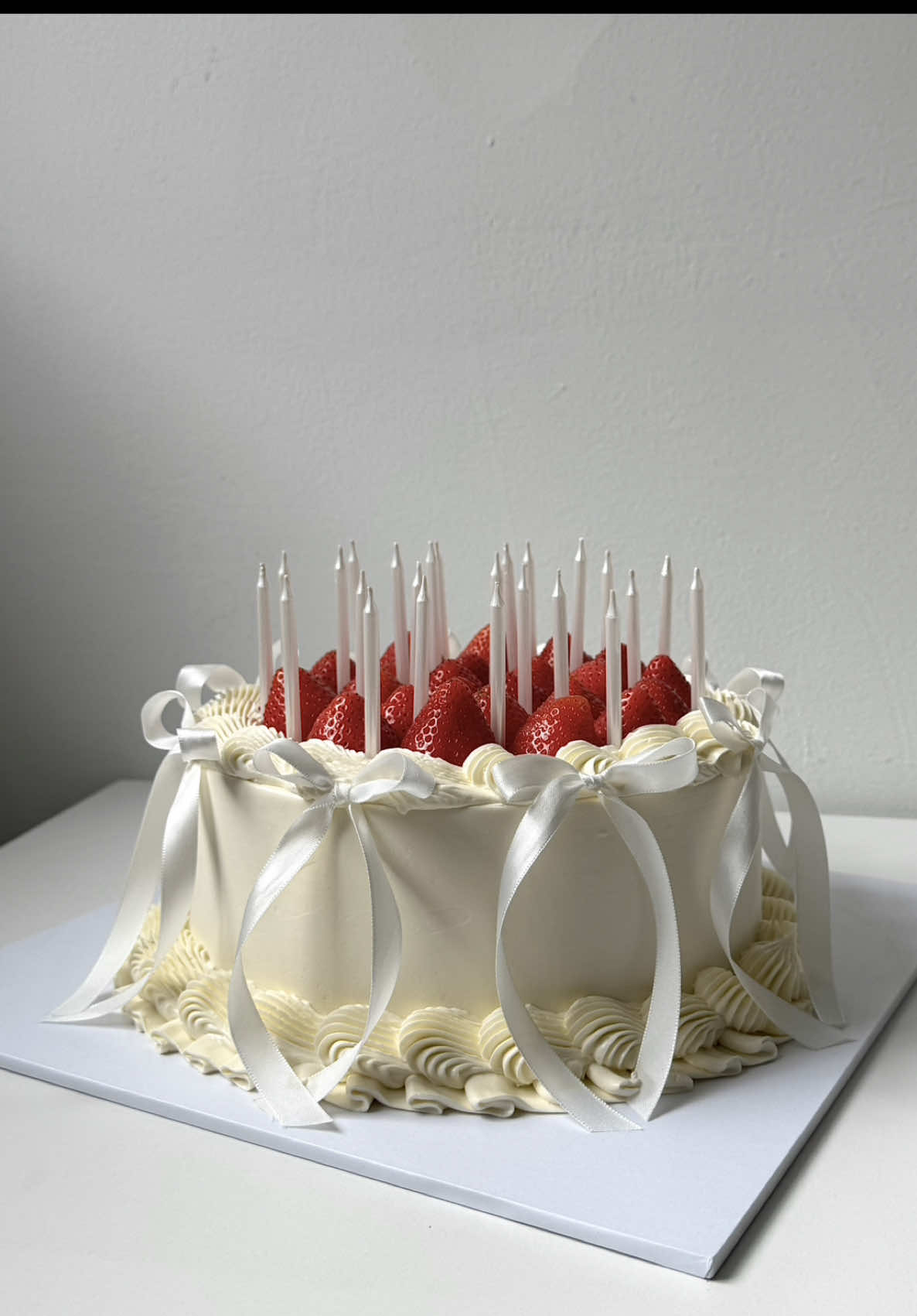 Elegant vintage style cake topped with fresh strawberries, white candles, and satin ribbon bows 🎂🤍